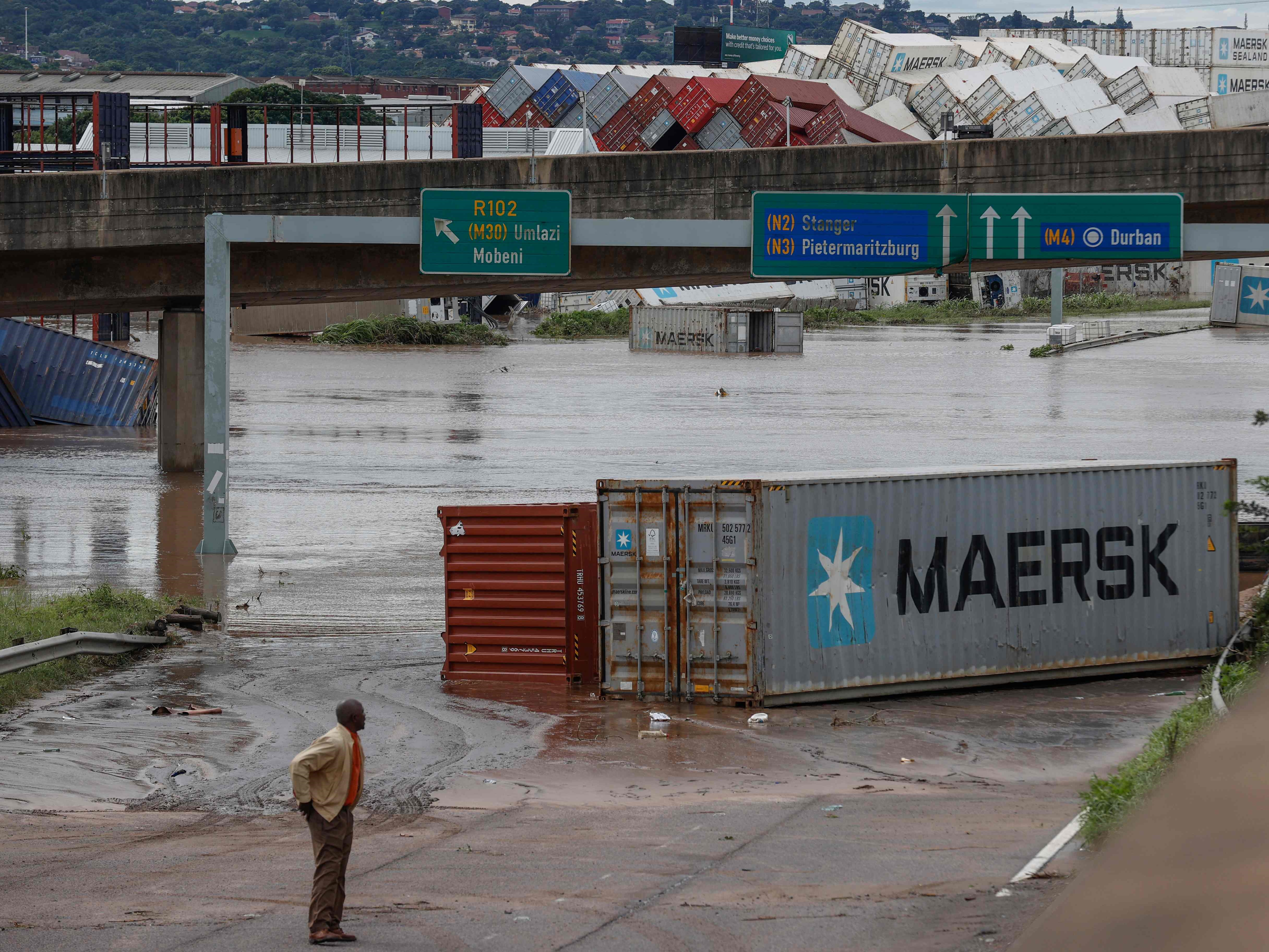 Seorang penduduk kota Umlazi melihat peti kemas yang jatuh di fasilitas penyimpanan peti kemas setelah hujan lebat dan angin kencang.