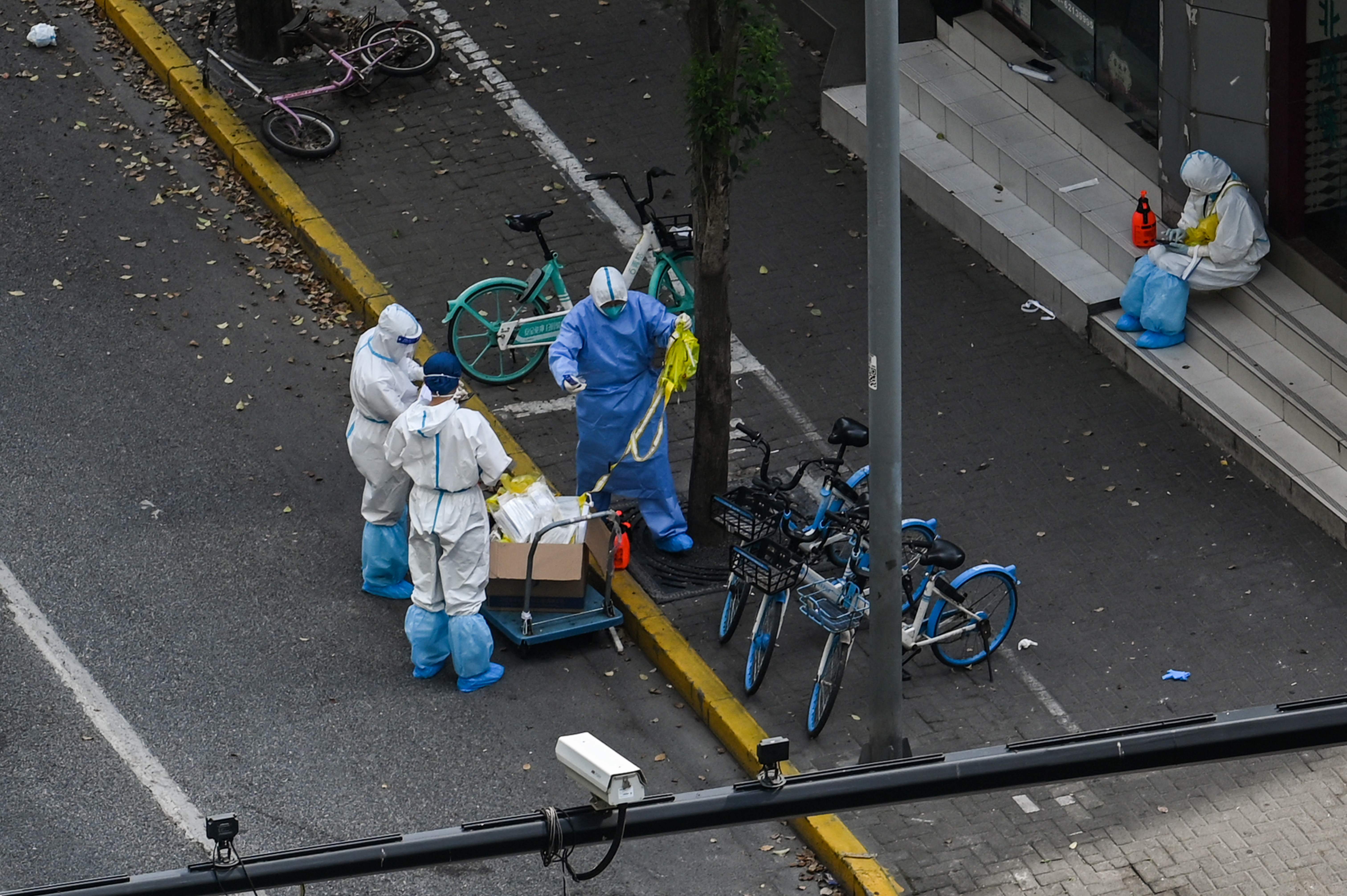 Petugas dengan menggunakan alat pelindung diri bersiaga di gerbang masuk permukiman di Distrik Jing'an, Shanghai, Tiongkok, Selasa (12/4). 