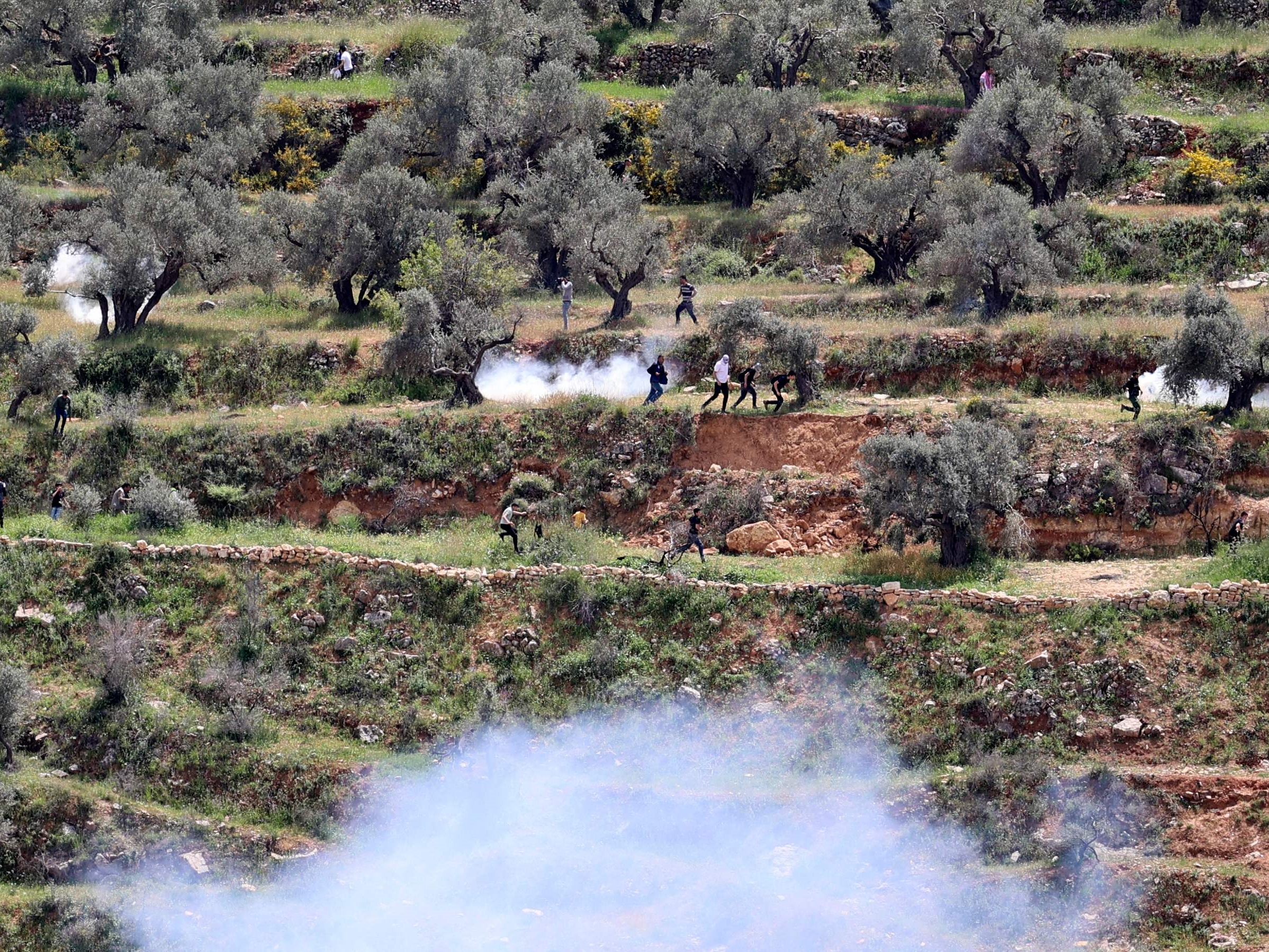 Pengunjuk rasa Palestina lari dari gas air mata yang ditembakkan oleh pasukan keamanan Israel selama demonstrasi menentang pemukiman ilegal.