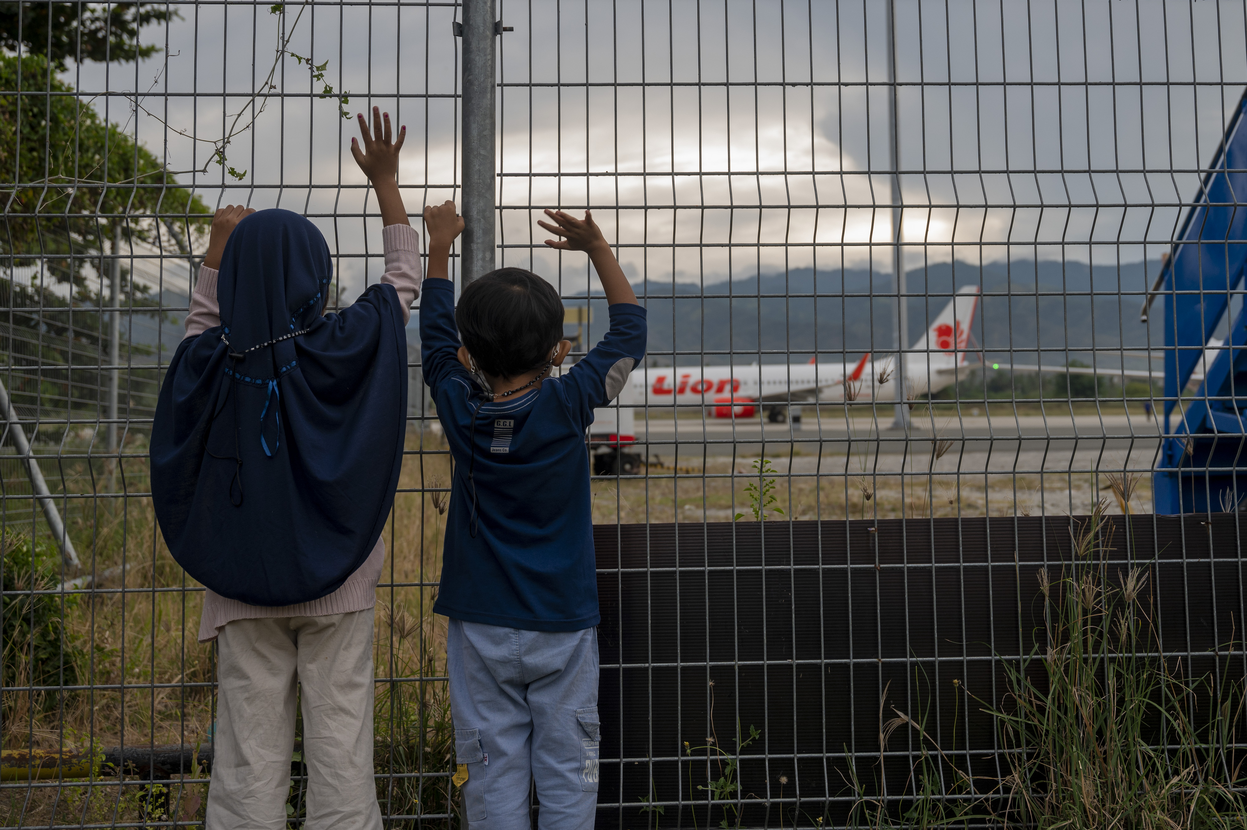 Dua orang anak melambaikan tangan kepada sebuah pesawat yang akan lepas landas di Bandara Mutiara Sis Aljufri, Palu, Sulawesi Tengah.
