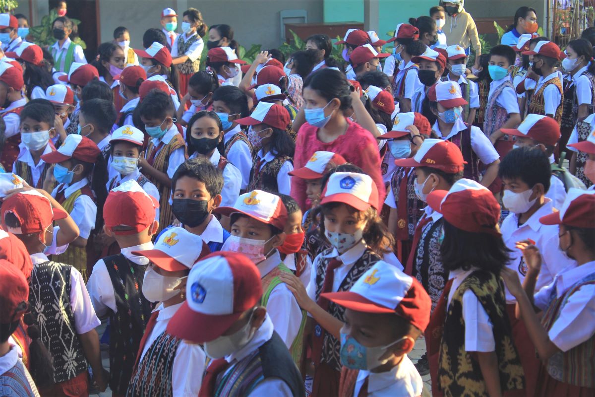  Seorang guru mengenakan pakaian adat berada di tengah siswa SD Katolik Santa Maria Assumpta, Kota Kupang, NTT, Kamis (21/4).