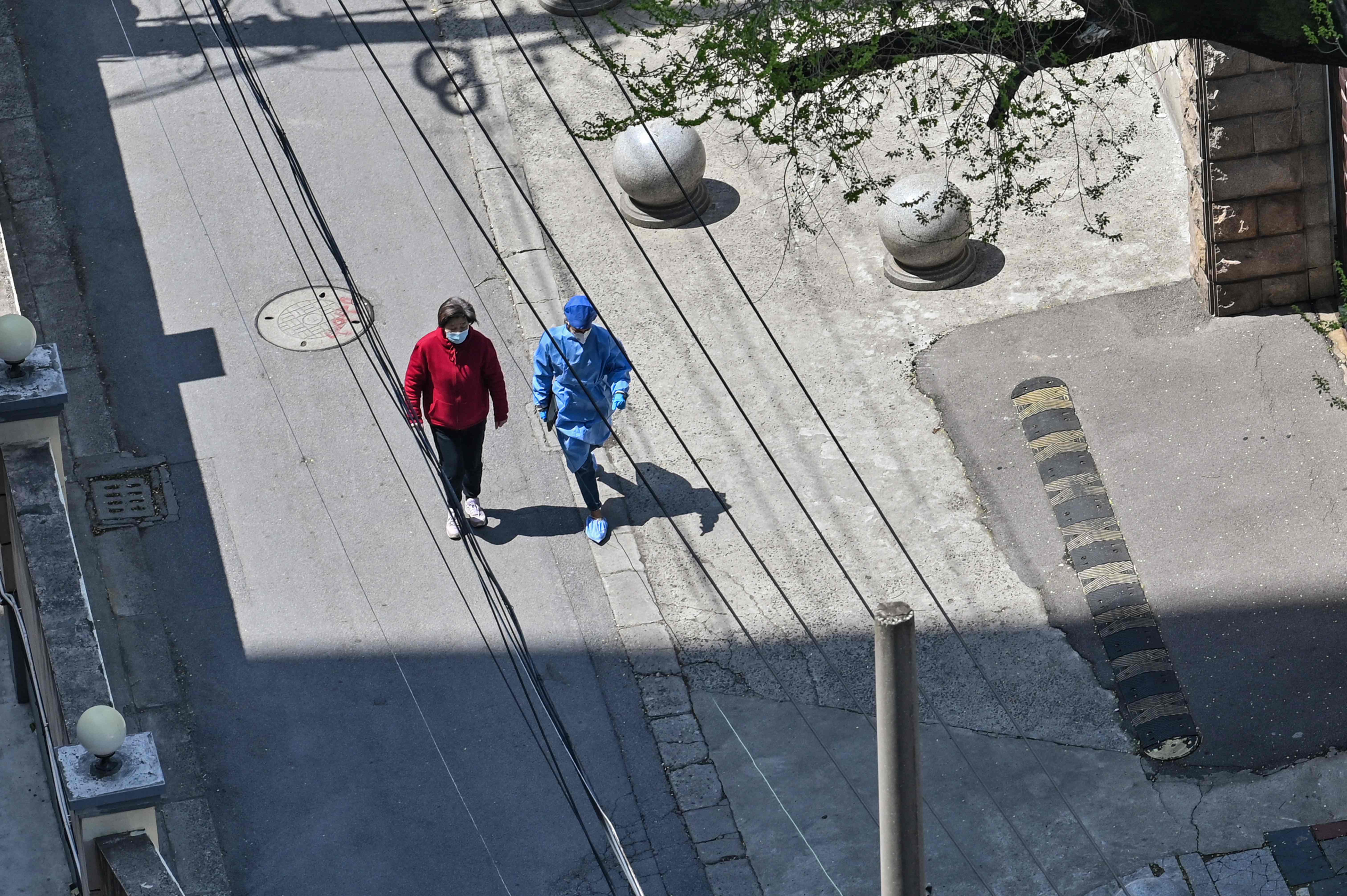 Seorang warga dan petugas yang pakai APD mengumpulkan makanan dari warga untuk warga lainnya di Kota Shanghai yang berlakukan 'lockdown'.