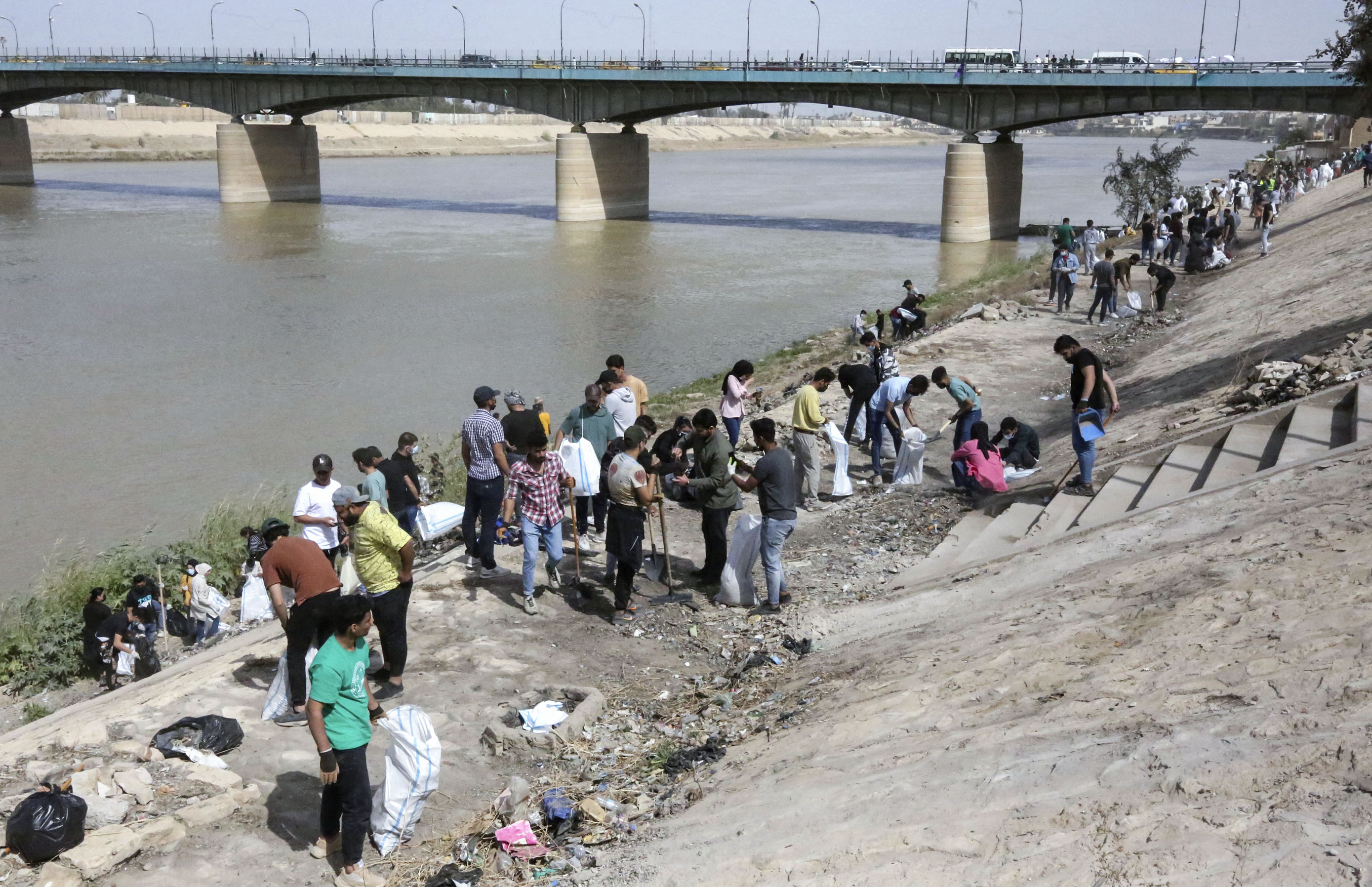 Para relawan memunguti sampah di tepi Sungai Tigris, Irak