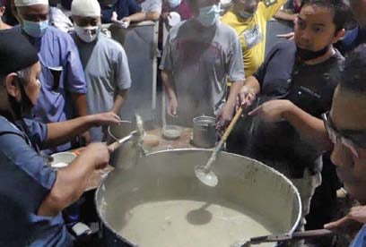 Petugas membagikan takjil bubur Samin Banjar kepada warga di halaman Masjid Darussalam, Surakarta, Jawa Tengah, Minggu (3/4).