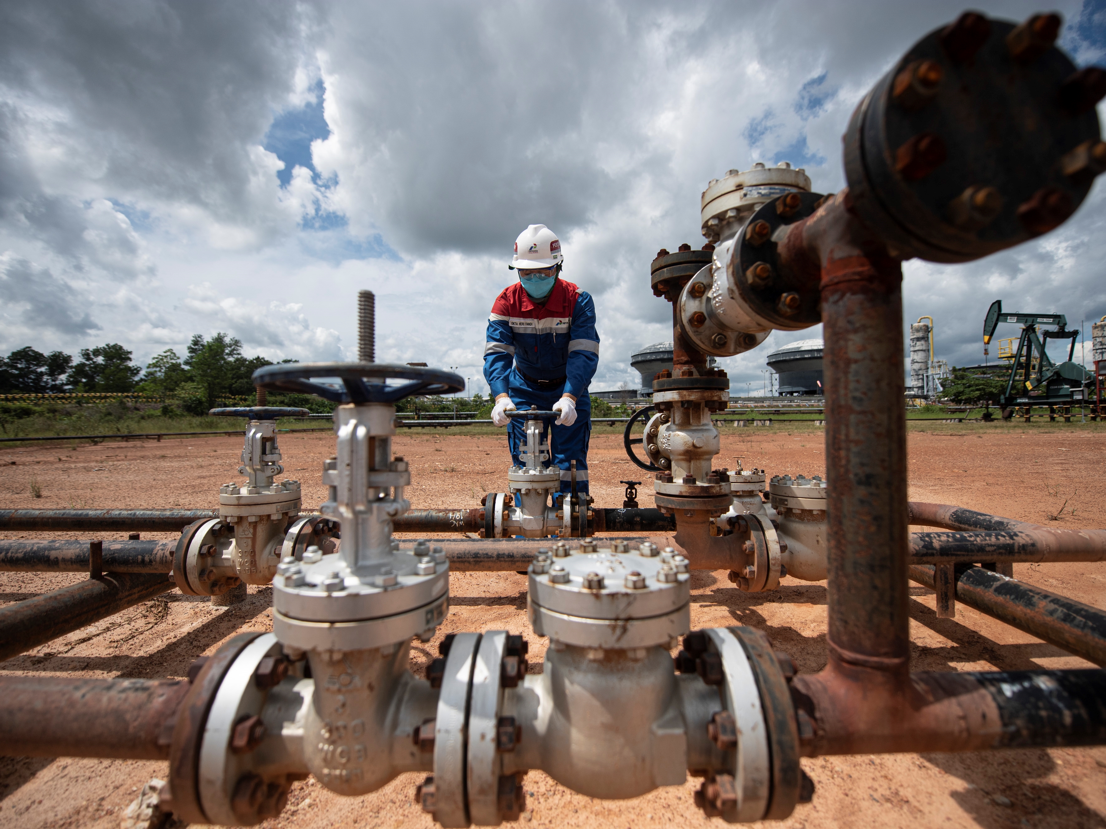 Pekerja PT Pertamina Hulu Rokan mengontrol kerangan pipa produksi yang berasal dari sumur menuju stasiun pengumpul minyak mentah.