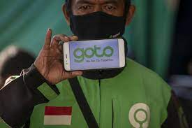 Pengemudi ojek daring Gojek menunjukkan logo merger perusahaan Gojek dan Tokopedia.