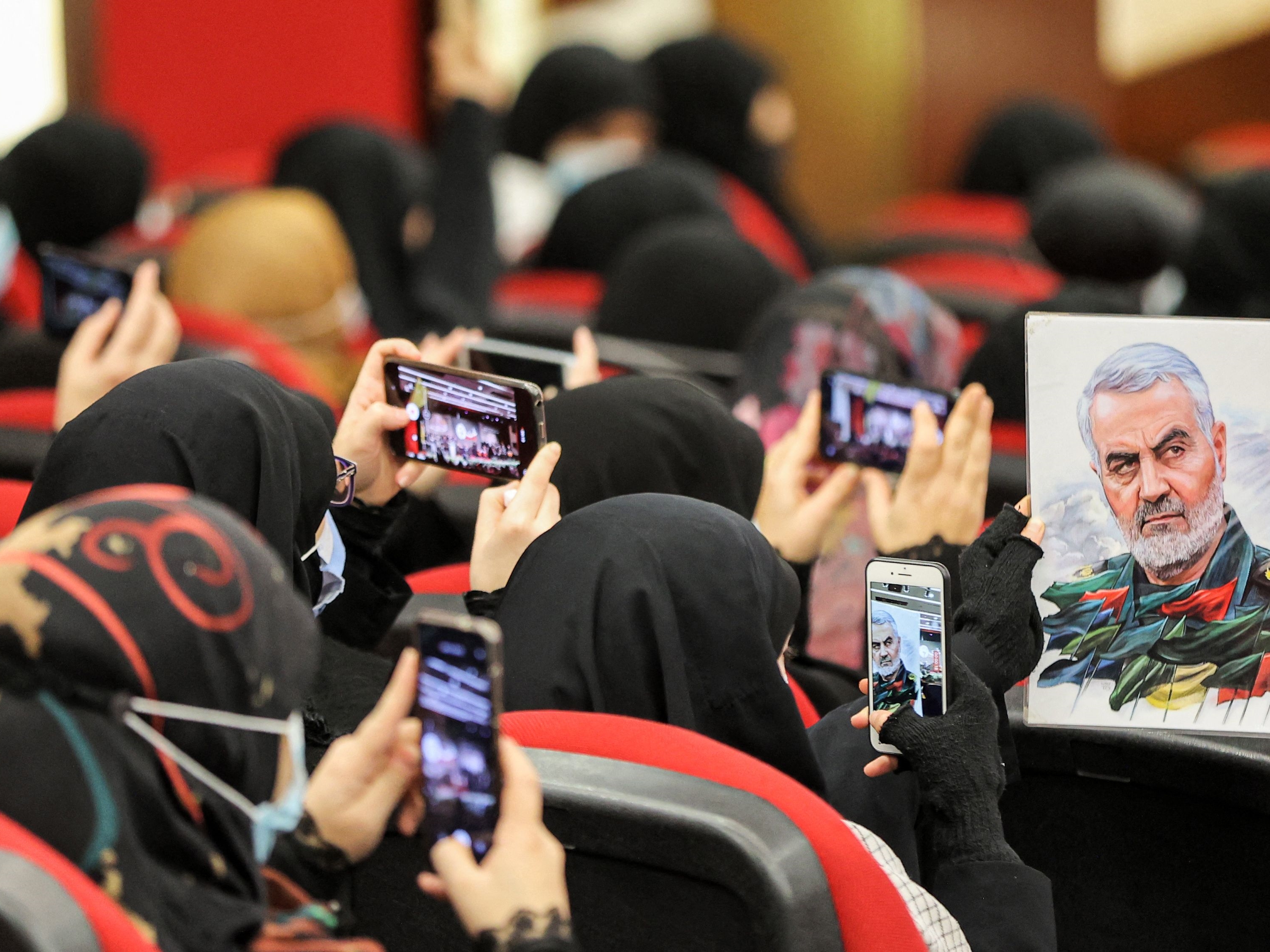 Seorang wanita memegang ilustrasi potret Qasem Soleimani, komandan puncak dari Korps Pengawal Revolusi Iran (IRGC), yang dibunuh AS.