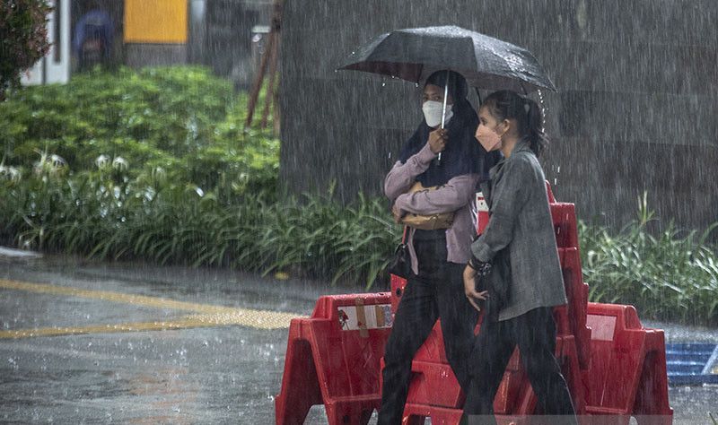 Warga berjalan Muhammad Adimaja saat hujan lebat di kawasan Sarinah Thamrin, Jakarta, Selasa (5/4/2022).