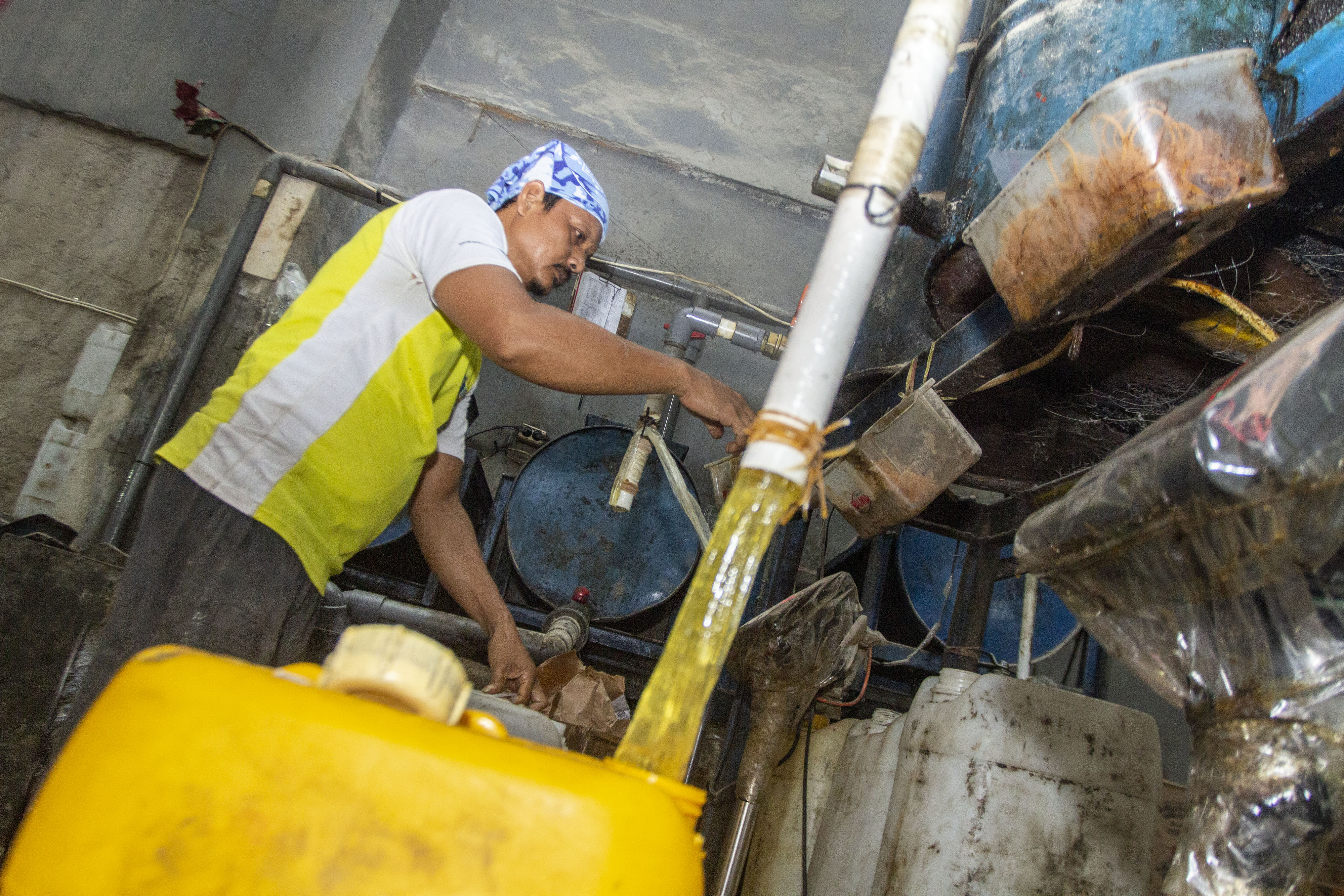 Pekerja mengisi minyak goreng curah kedalam jeriken