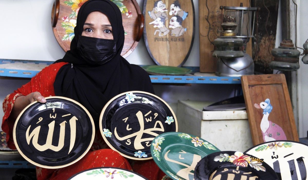 Perajin menunjukkan lukisan kaligrafi Arab pada piring keramik di rumah produksi Fairus Art, Desa Plumbon, Sukoharjo, Jawa Tengah.