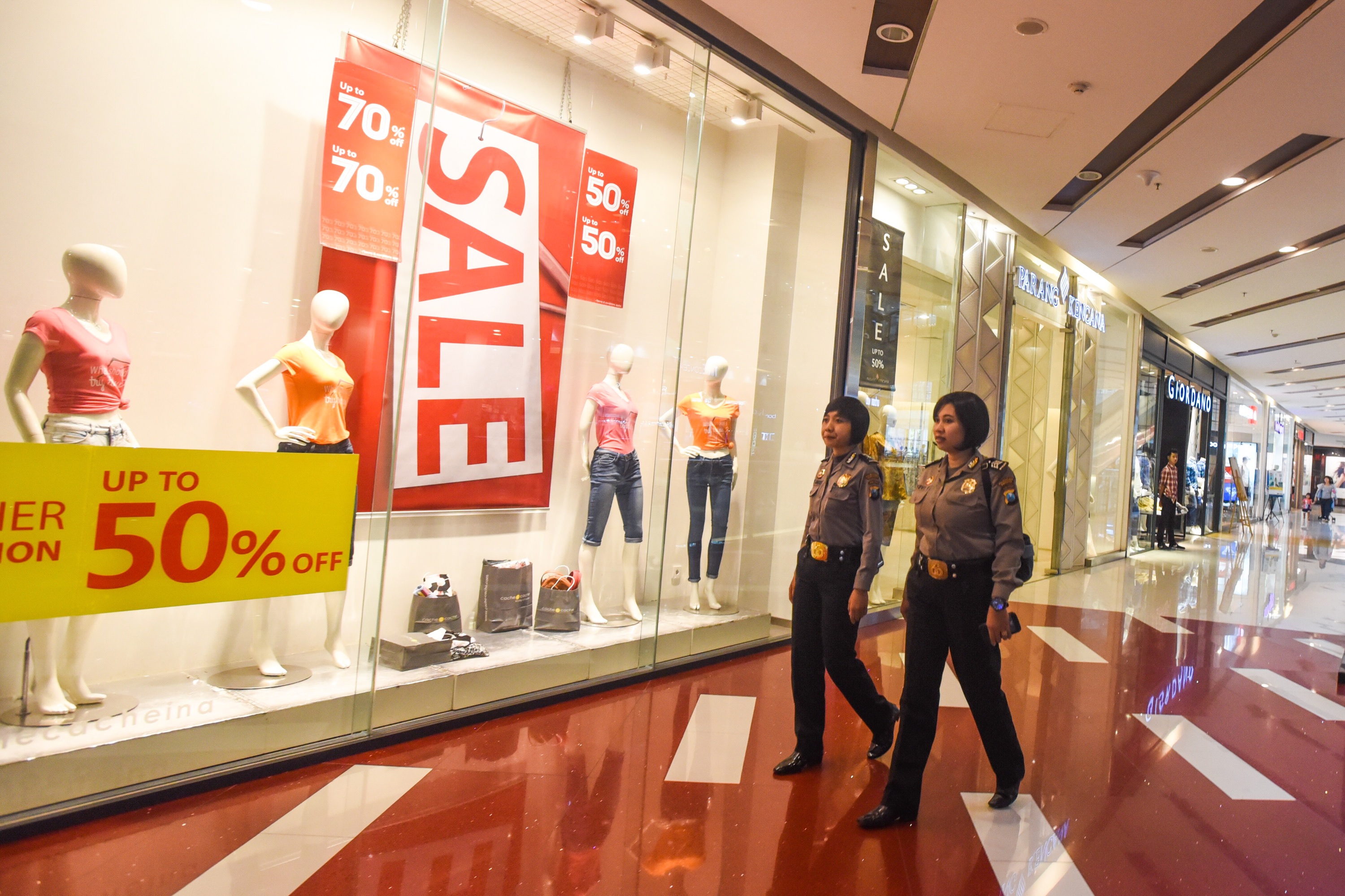 Polwan melintas di depan toko yang menawarkan potongan harga ketika patroli pengamanan Ramadan di salah satu pusat perbelanjaan Surabaya, Ja
