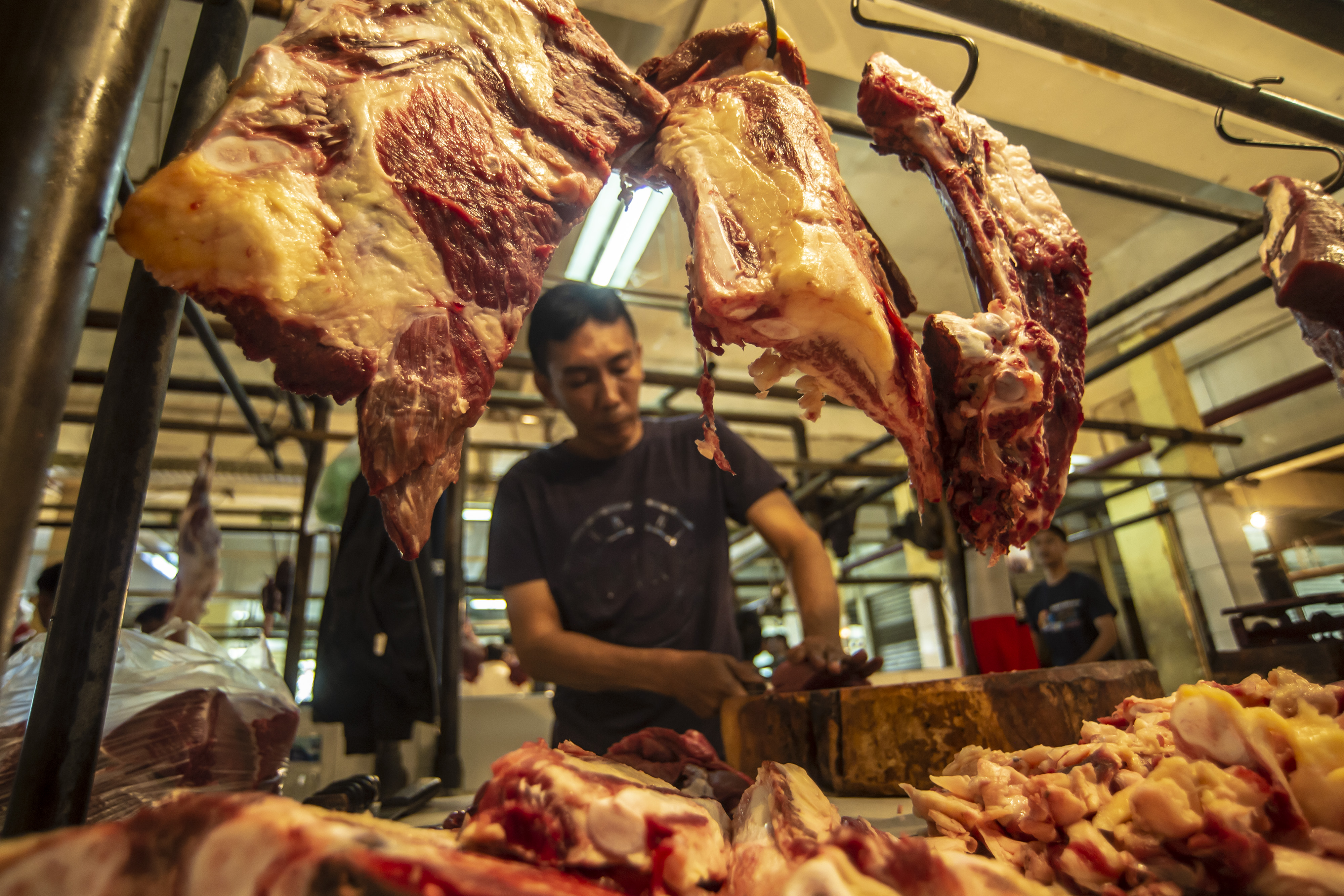 Ilustrasi pedagang memotong daging sapi di pasar.