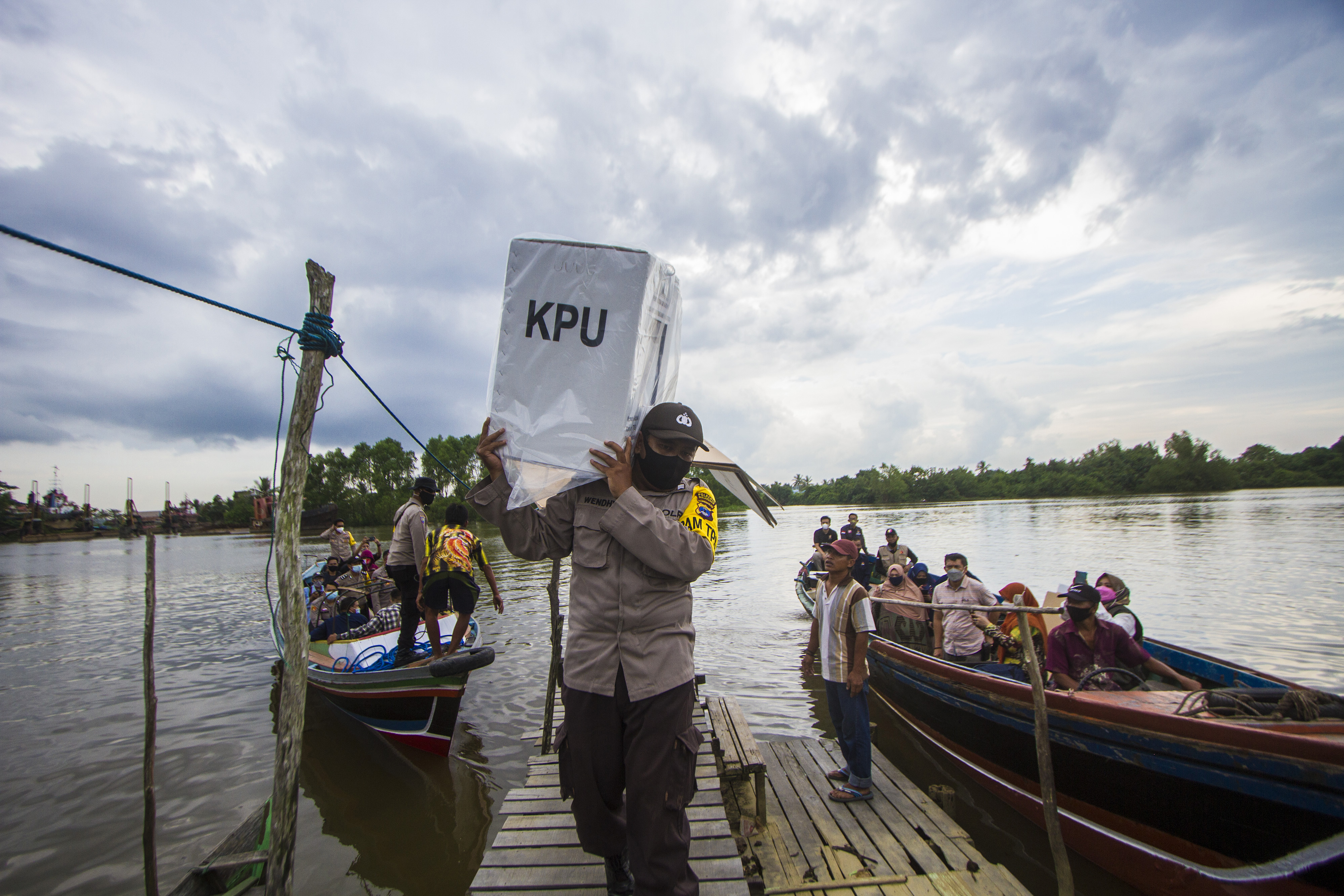 Polisi membawa kotak suara saat mendistribusikan logistik pemilu di Kalimantan Selatan.