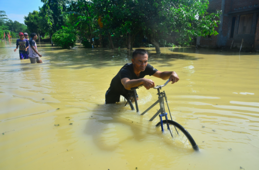 Warga melintas di jalan yang tergenang air di Desa Cingrong, Purwodadi, Grobogan, Jawa Tengah, Rabu (16/3/2022).