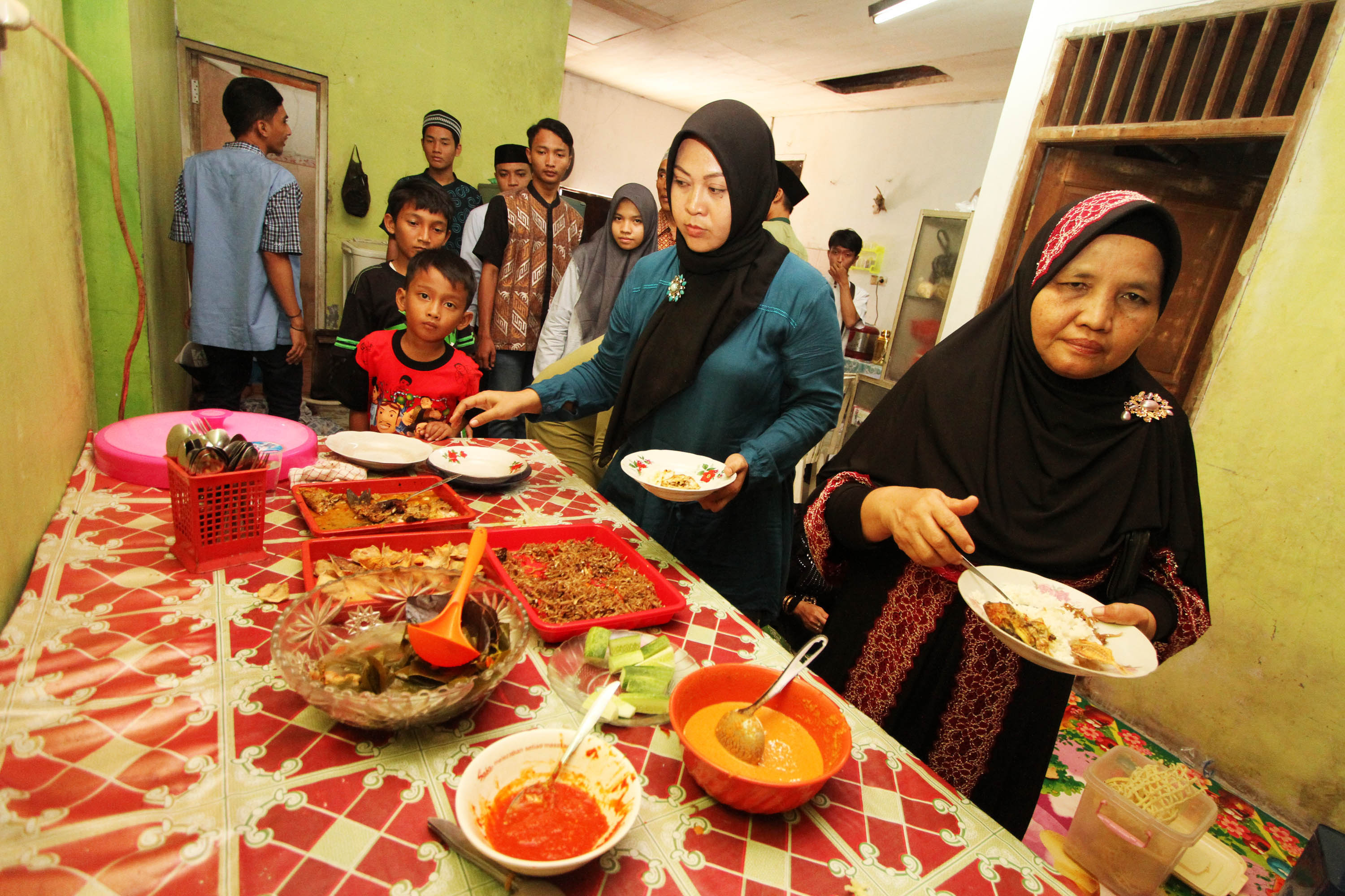 Warga menyantap hidangan yang disajikan tuan rumah saat bersilaturahim bersama keluarga serta kerabat di kawasan Duri Kosambi, Jakarta.