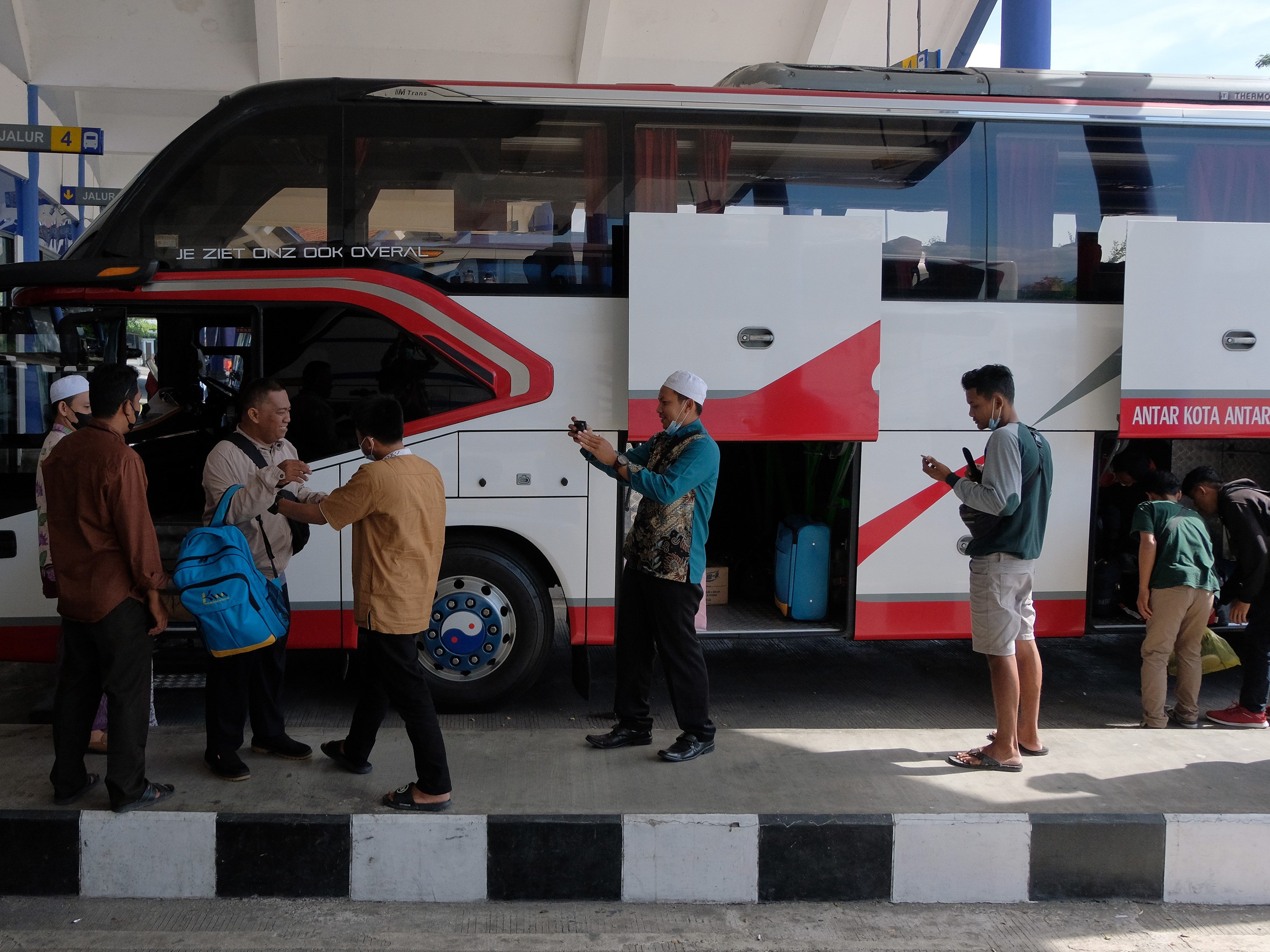 Penumpang bersiap-siap memasuki bus angkutan kota antarprovinsi saat mudik ke kampung halaman di Terminal Mengwi, Badung, Bali, Senin (11/4)