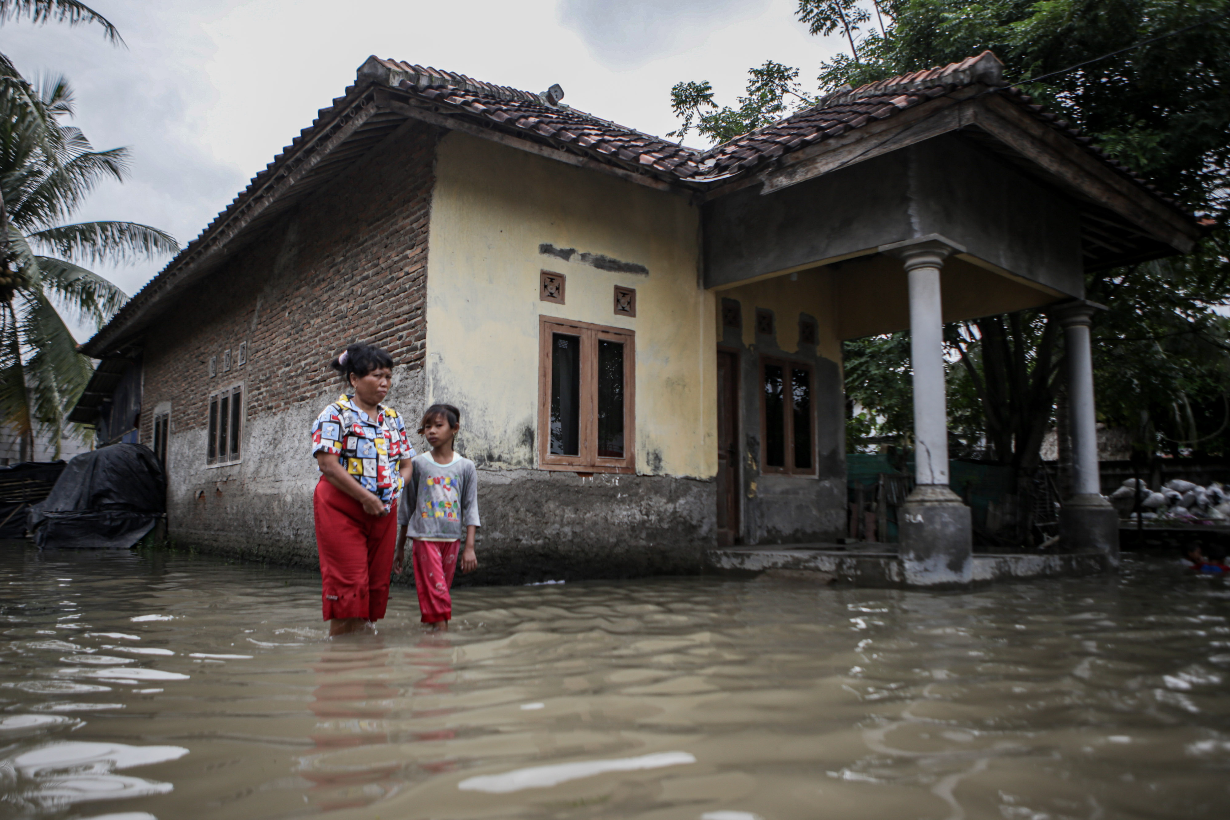 Ilustrasi: Warga berjalan di tengah banjir di Pakuhaji, Kabupaten Tangerang, Banten
