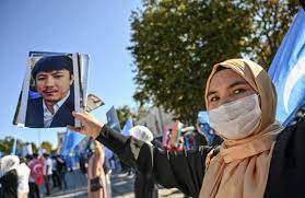 Para pengunjuk rasa dari muslim Uighur menunjukkan foto keluarganya yang hilang saat demonstrasi di Istanbul, Turki.