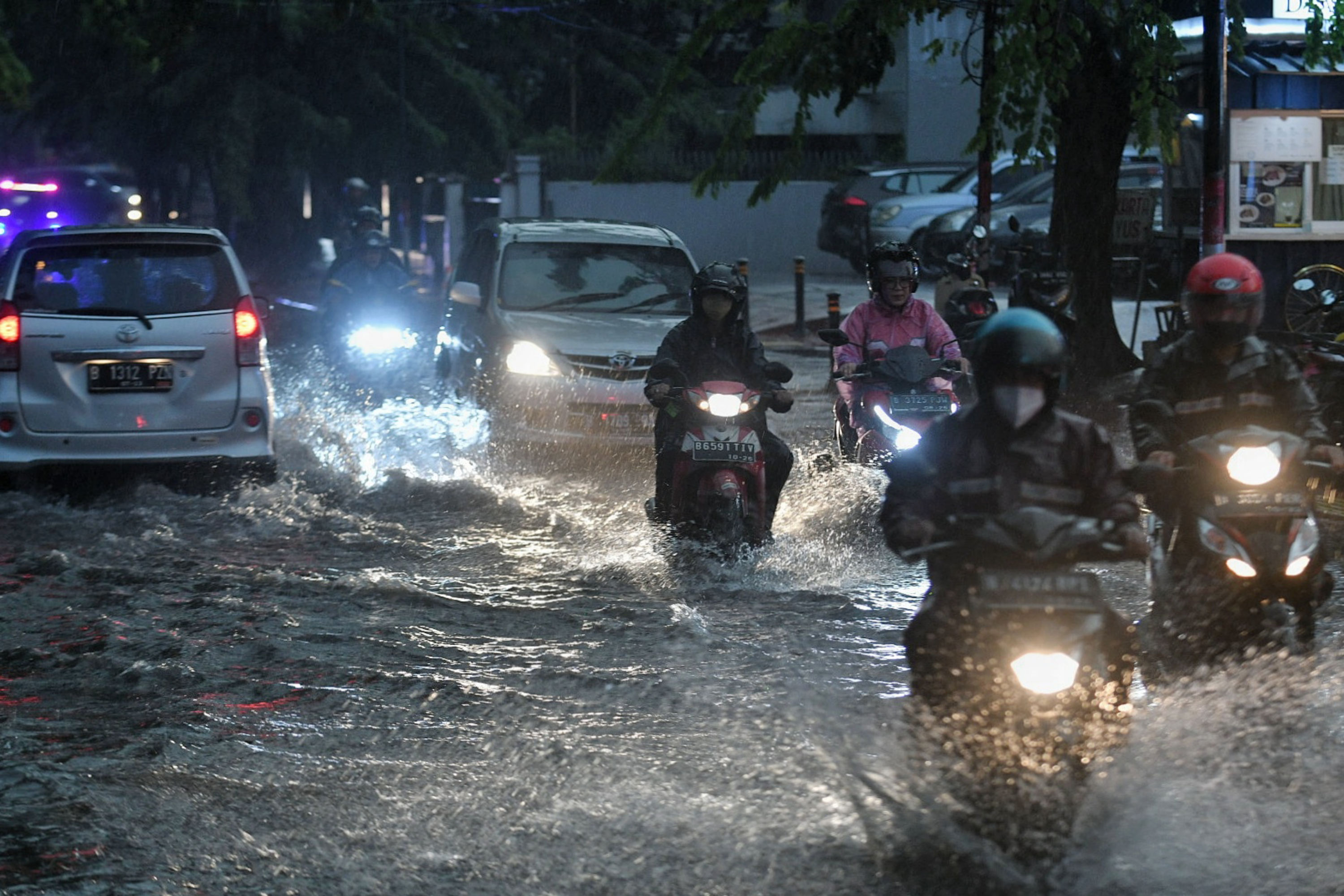 Pengendara melintasi banjir yang menggenangi jalan di wilayah Jakarta.