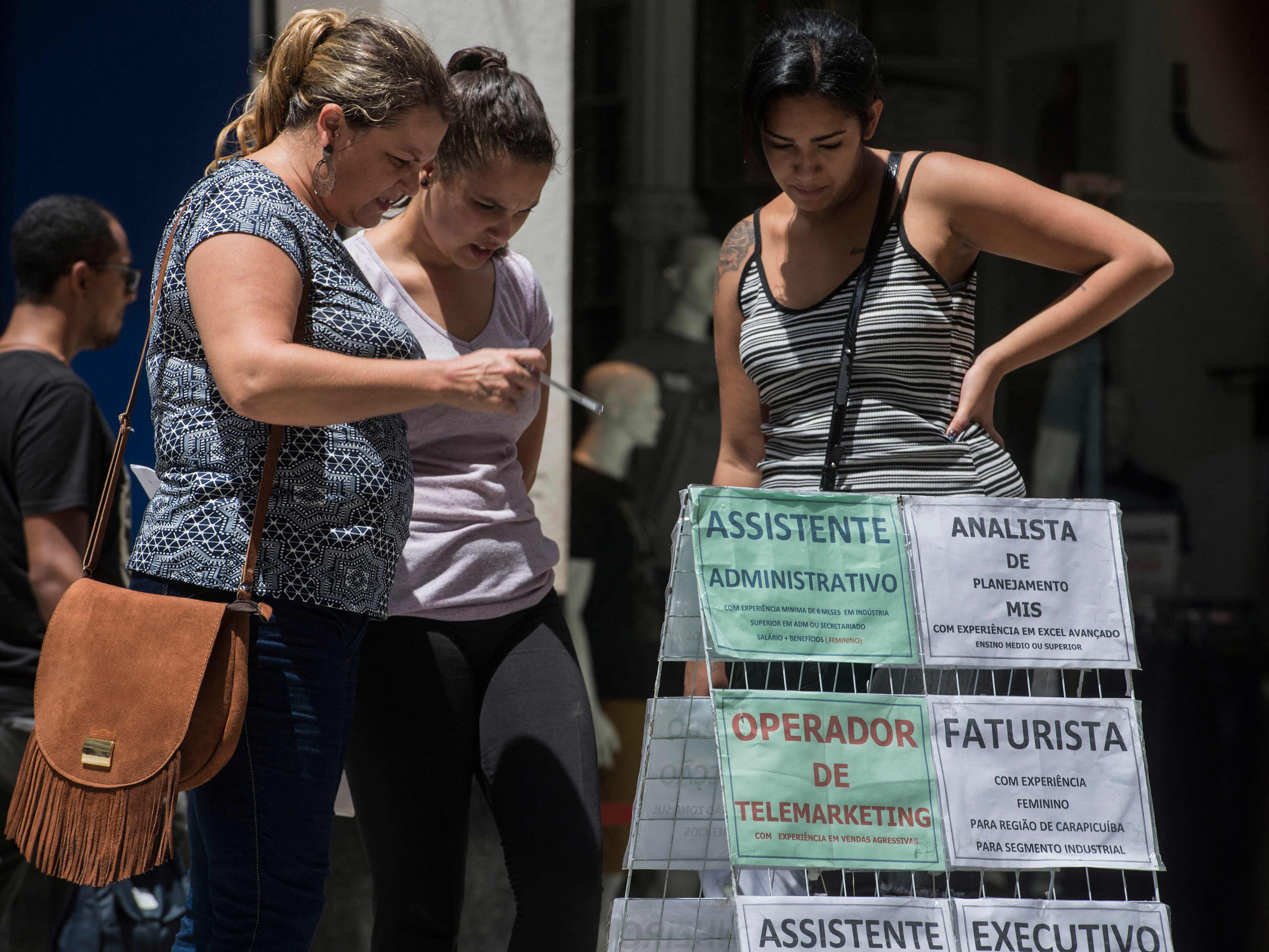 Warga yang tidak menganggur membaca pengumuman tawaran pekerjaan di pusat kota Sao Paulo, Brasil. 