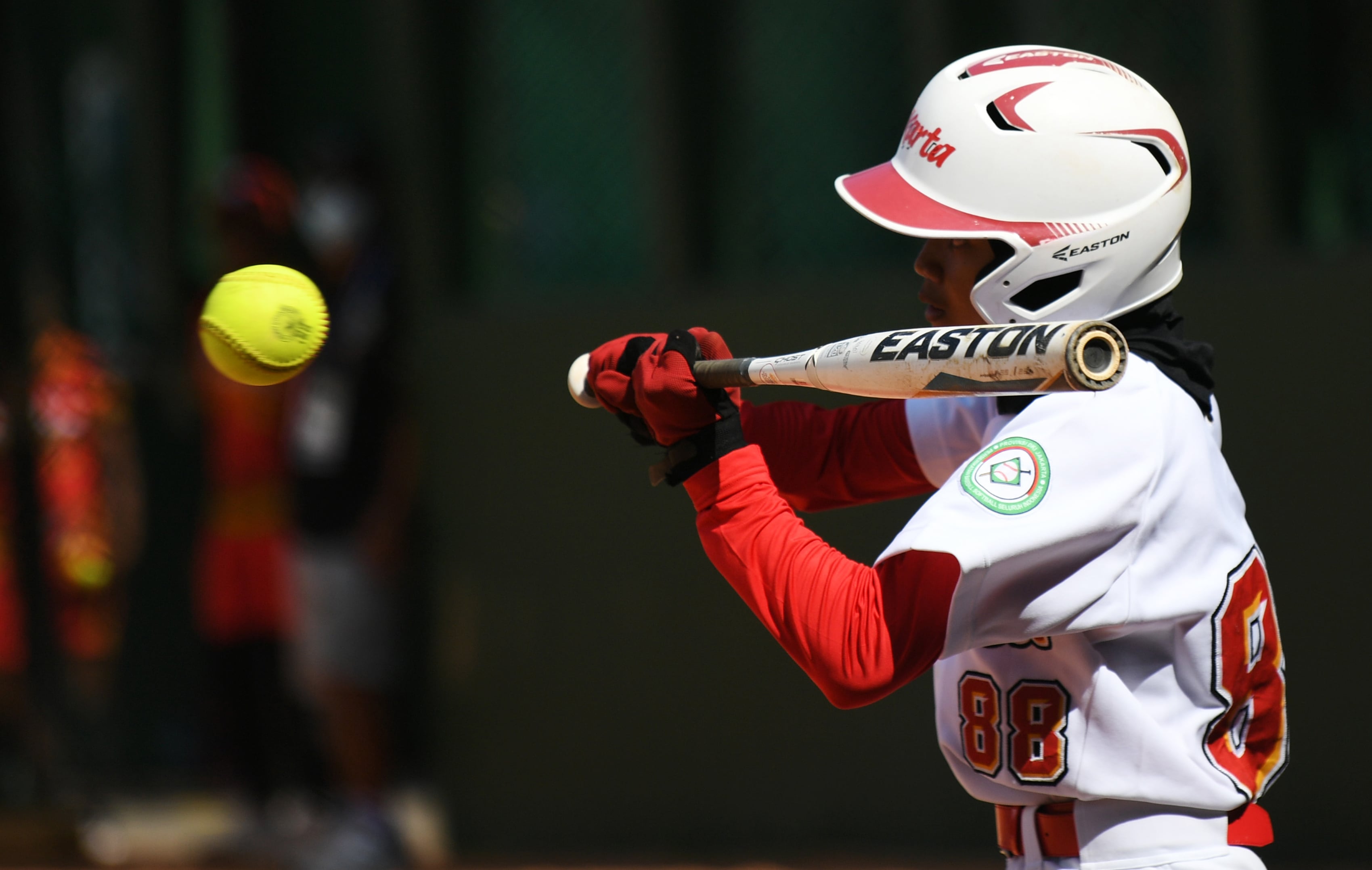 Ilustrasi atlet sofbol saat memukul bola lemparan.