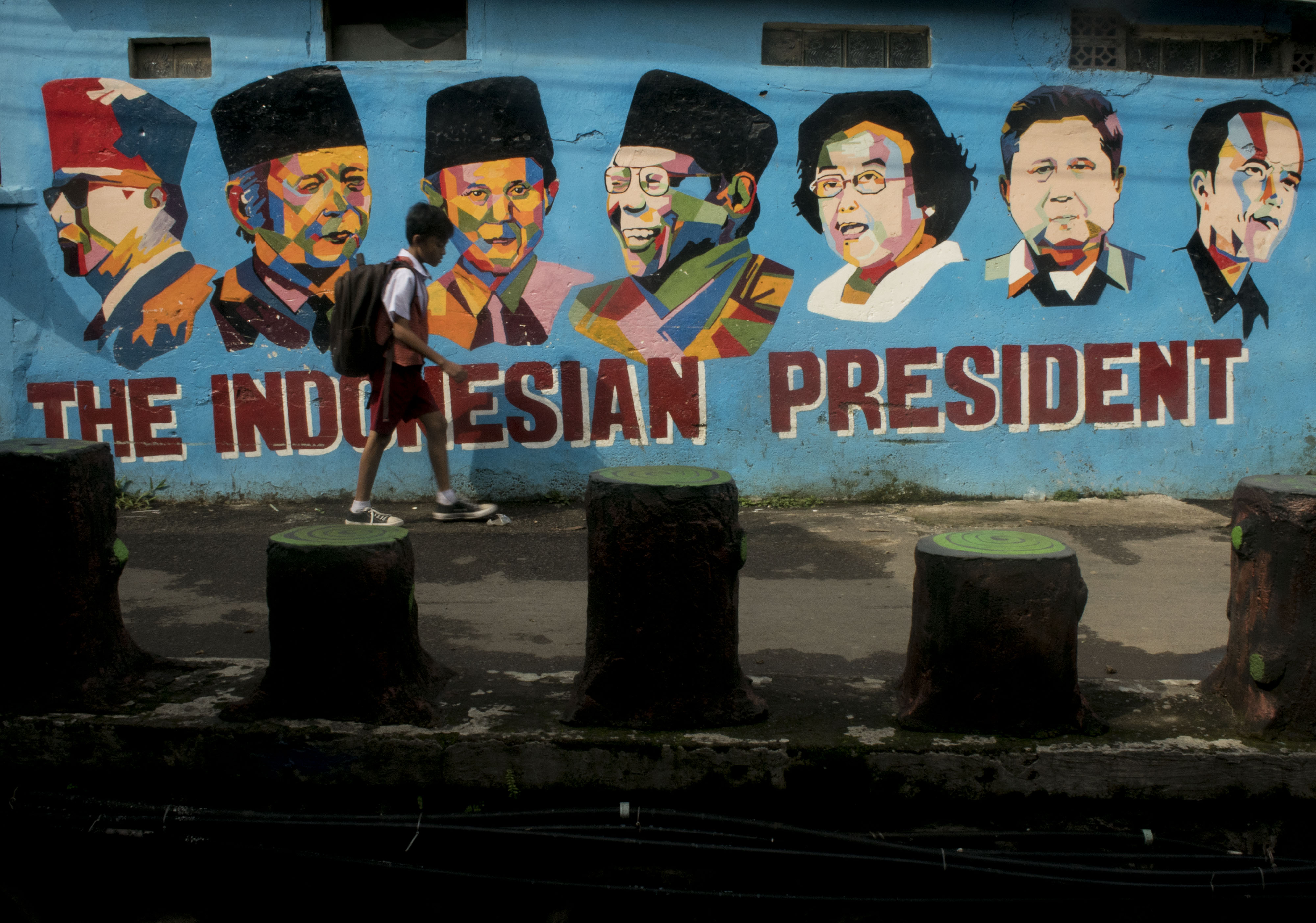 Pelajar melintasi mural bertema wajah Presiden Indonesia di wilayah Bandung, Jawa Barat.