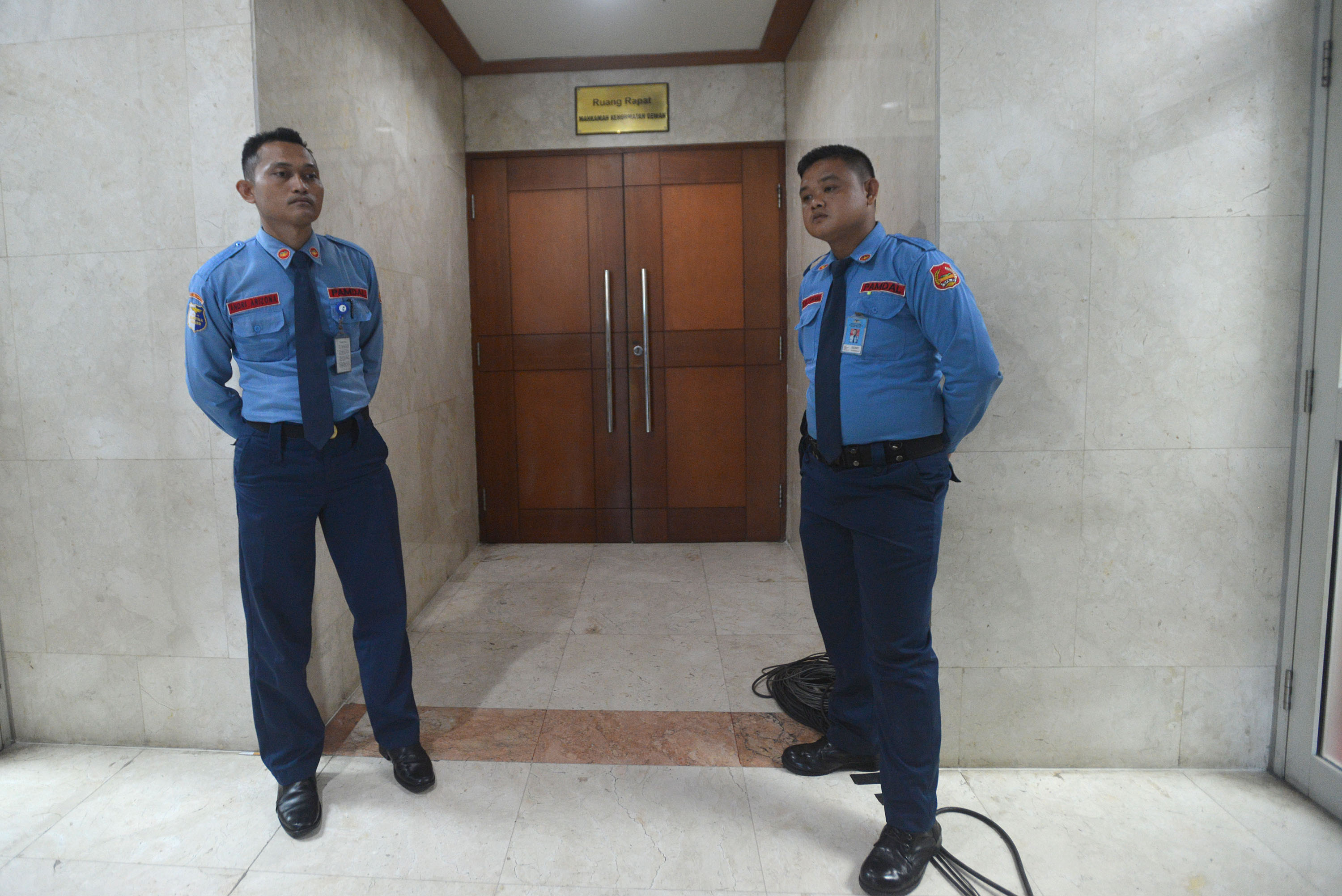 Dua anggota pengamanan dalam (Pamdal) berjaga di depan ruangan dalam rapat tertutup.
