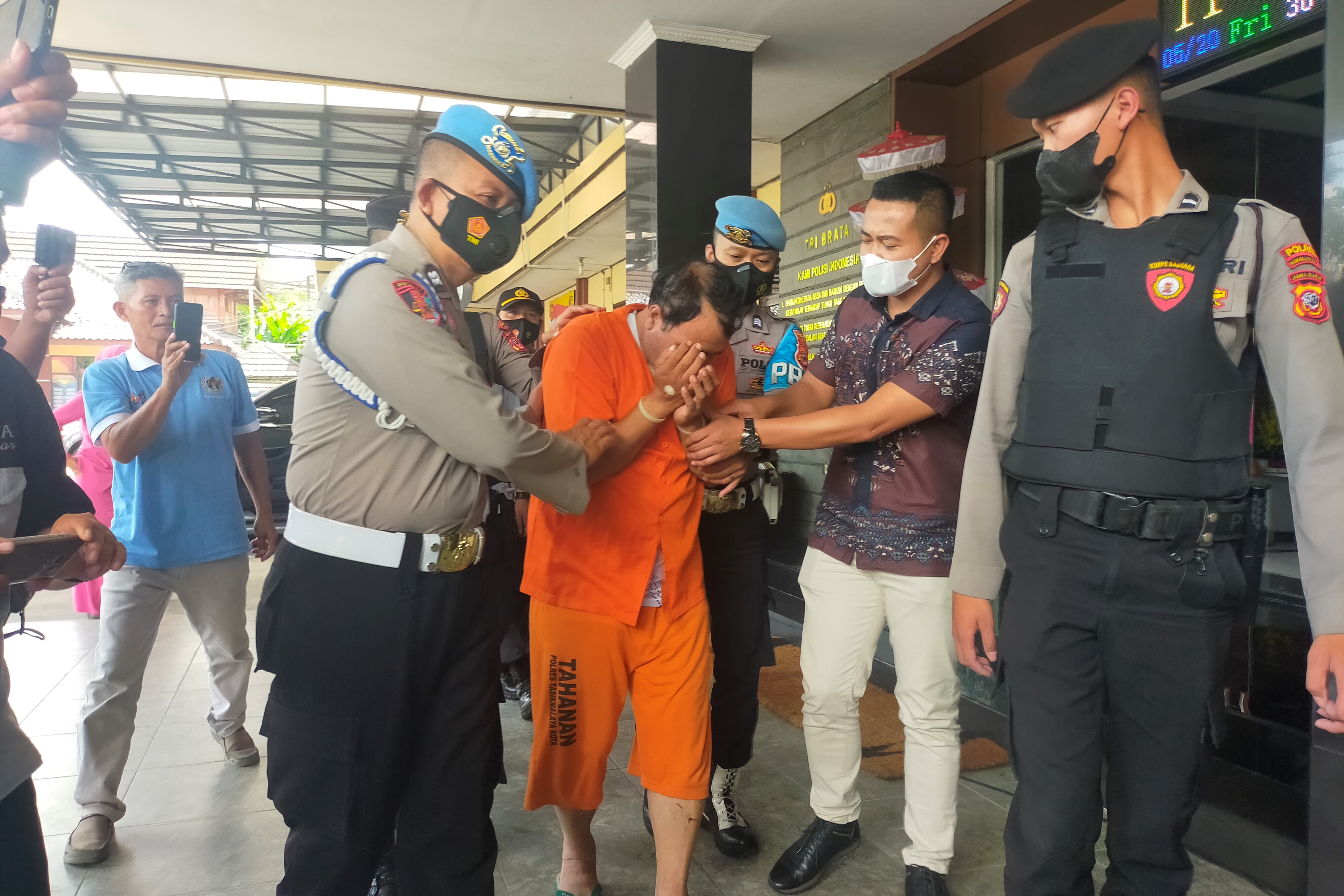 Tersangka pembunuhan mantan istrinya berstatus WNA asal Pakistan menutup wajah di kantor polisi.