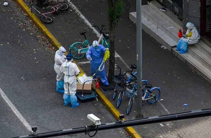 Petugas dengan menggunakan alat pelindung diri bersiaga di gerbang masuk permukiman di Distrik Jing'an, Shanghai, Tiongkok, Selasa (12/4).  