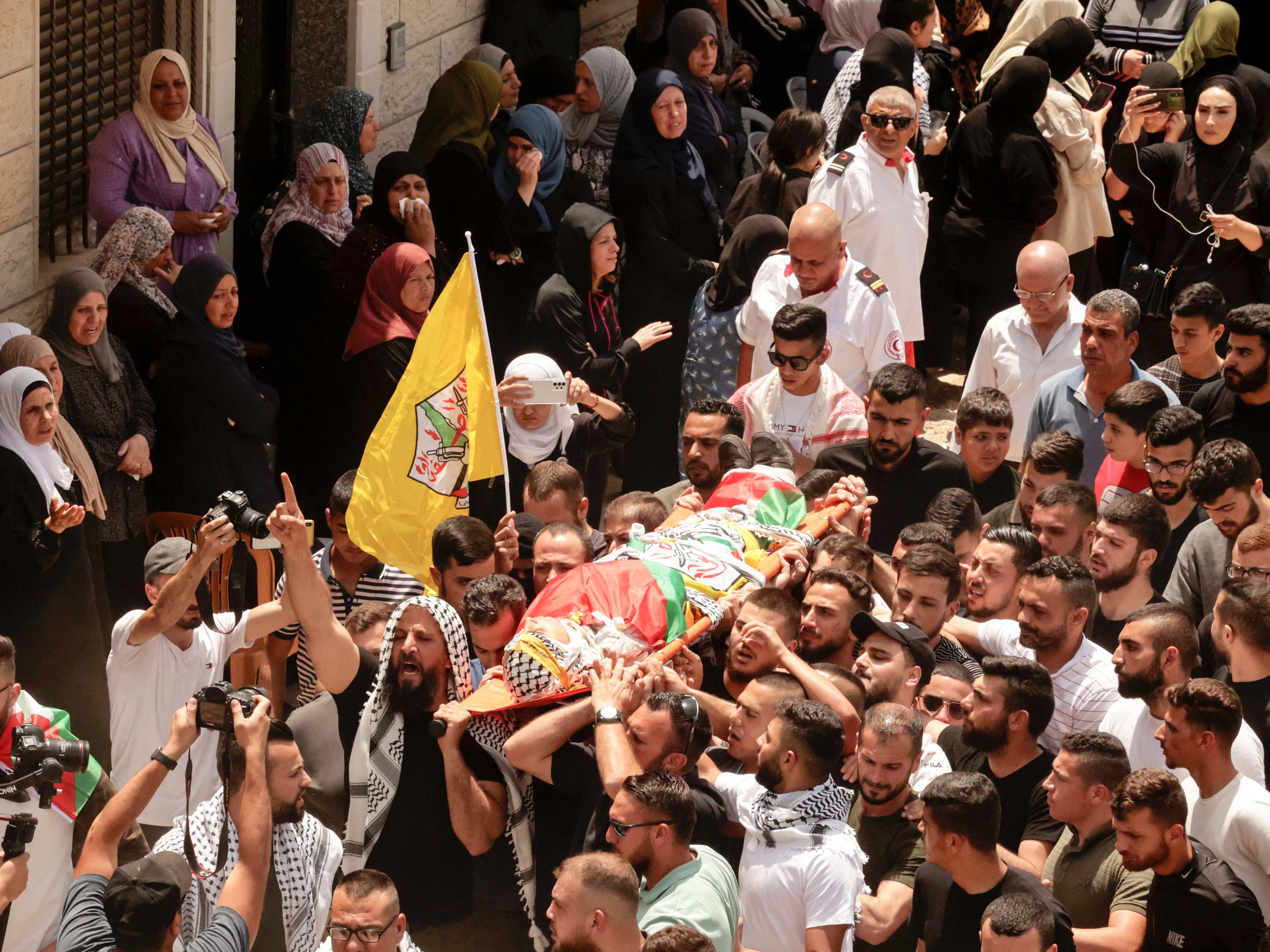 Pelayat Palestina membawa tubuh Zayd Mohammed Ghouneim yang terbungkus bendera selama pemakamannya di kota Al-Khader, Sabtu (28/5).