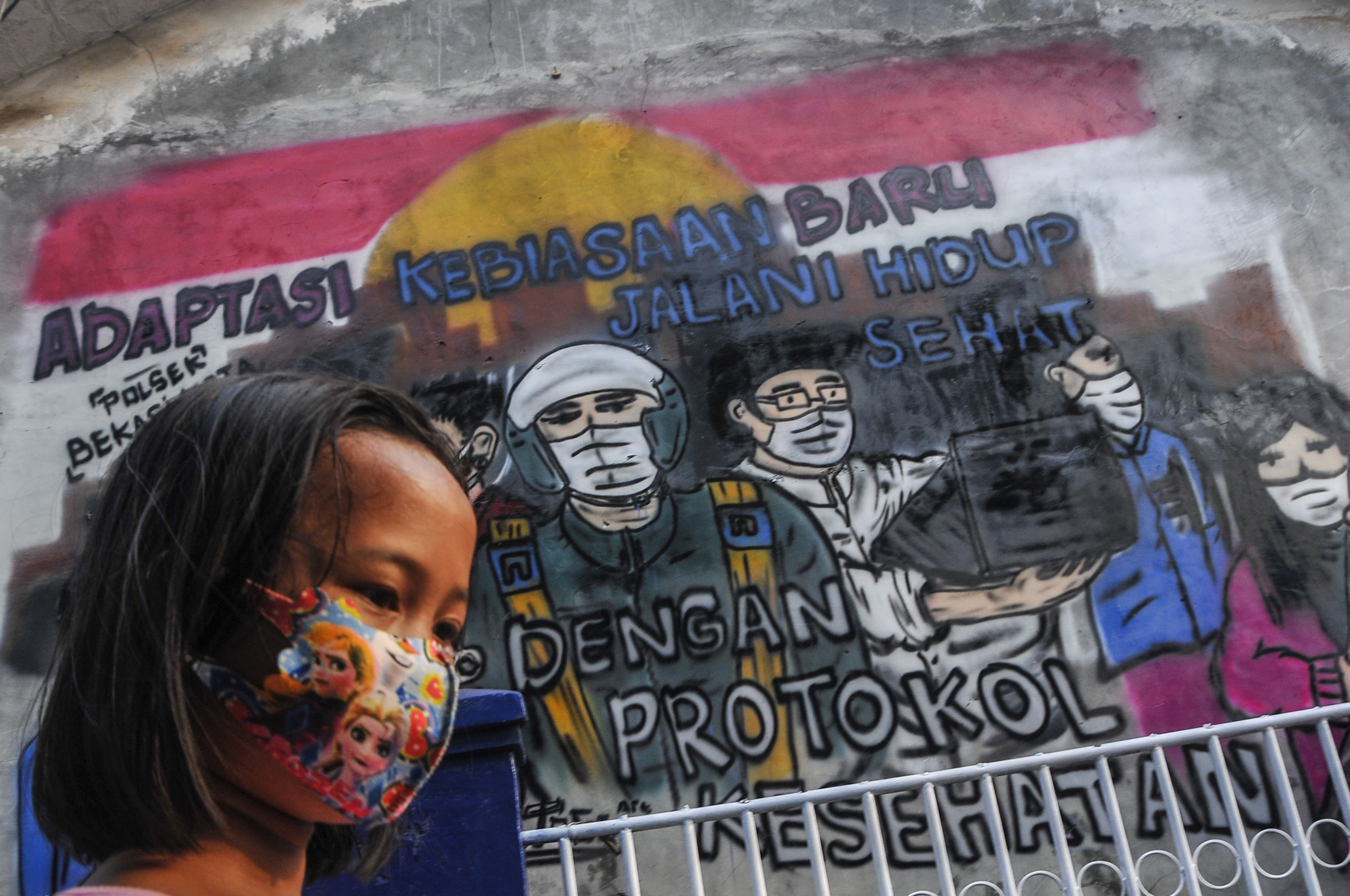Ilustrasi seorang anak melintasi mural terkait protokol kesehatan.
