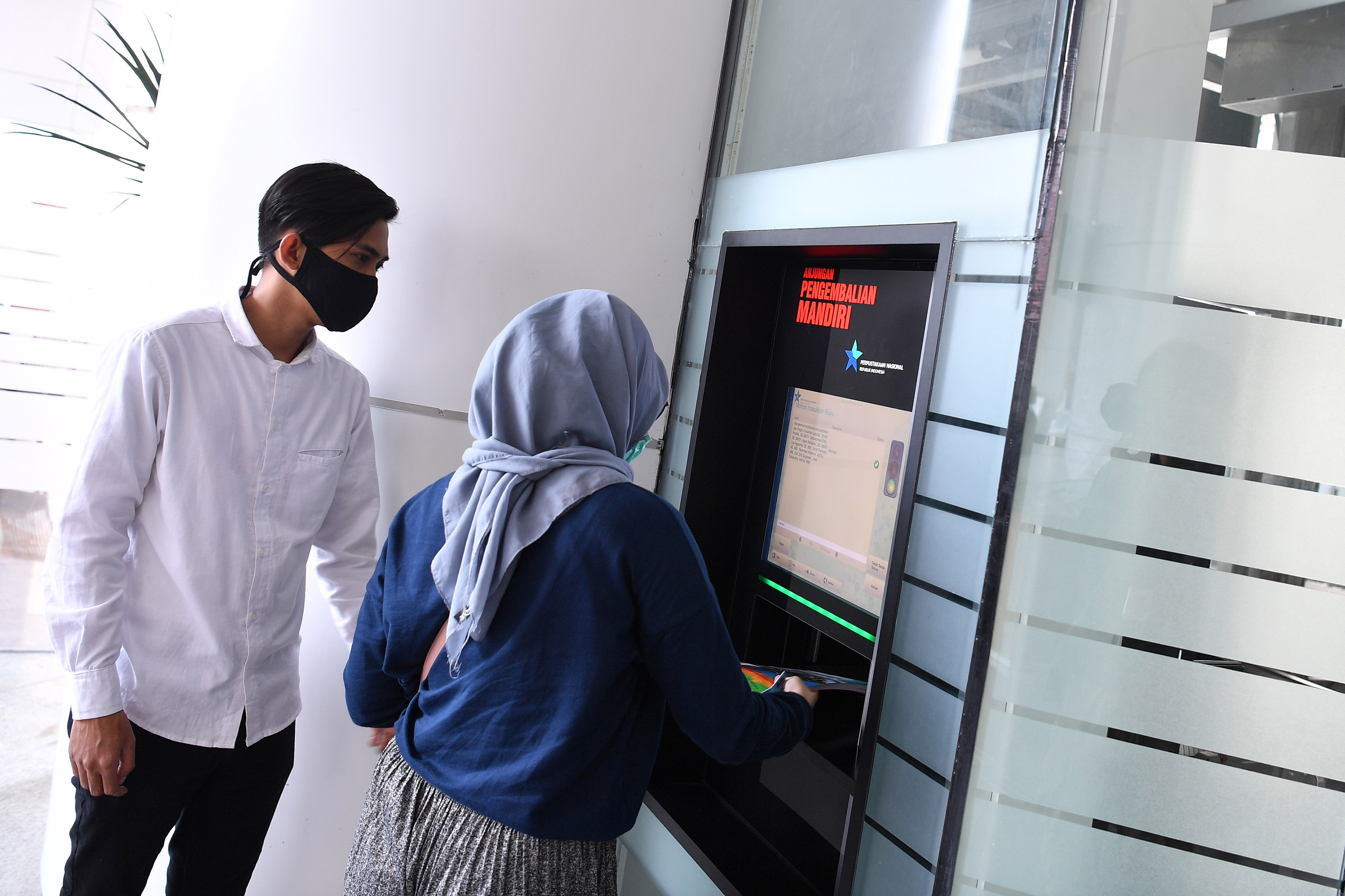  Warga mengembalikan buku yang dipinjam melalui Anjungan Pengembalian Mandiri di Perpustakaan Nasional, Jakarta, Senin (22/3/2021).