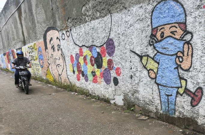 Pengendara motor melintasi mural bertemakan sosialisasi untuk vaksinasi COVID-19 di Bekasi, Jawa Barat, Senin (15/11/2021). 