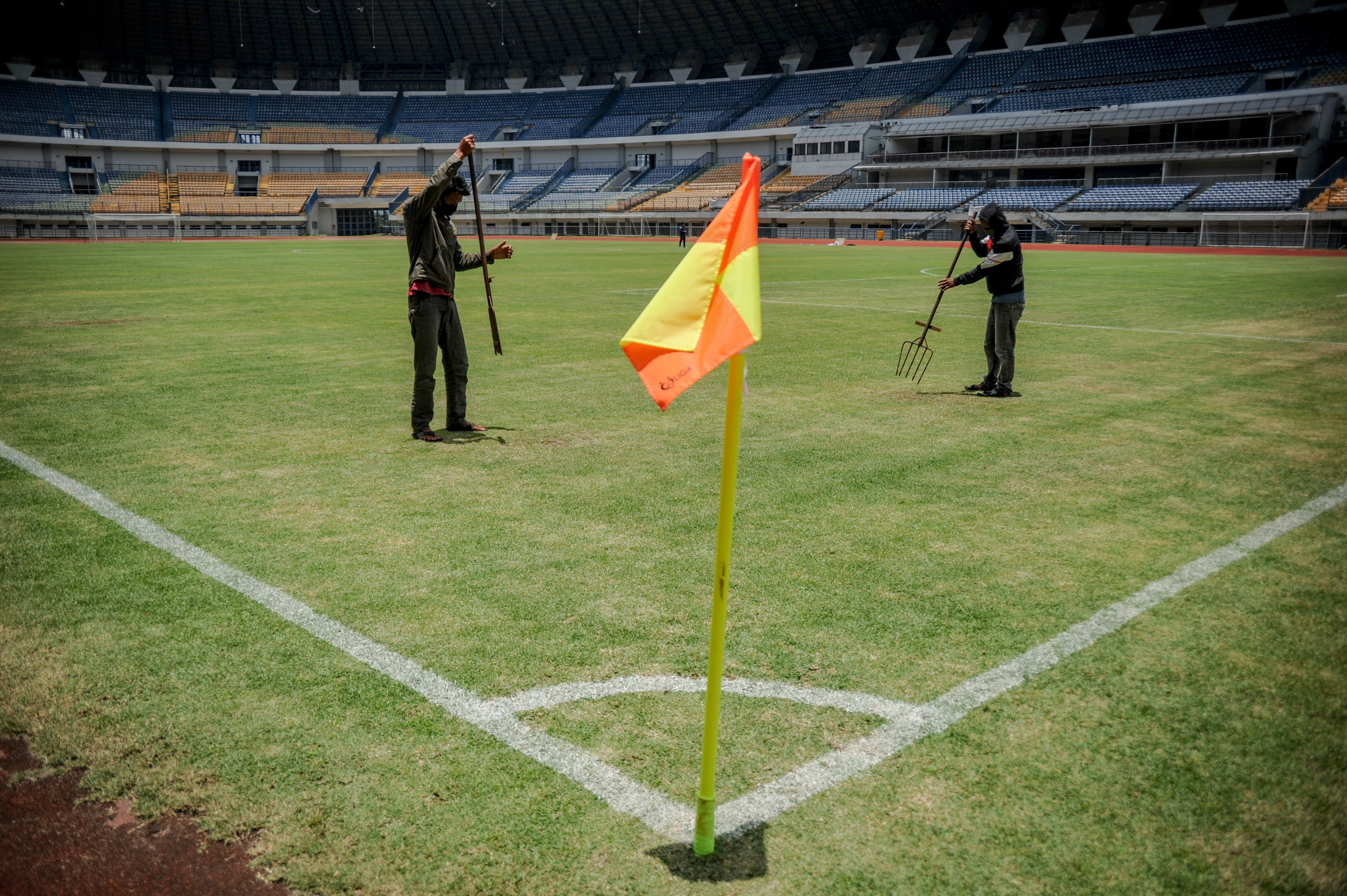 Pekerja tengah membersihkan rumput di Stadion Gelora Bandung Lautan Api