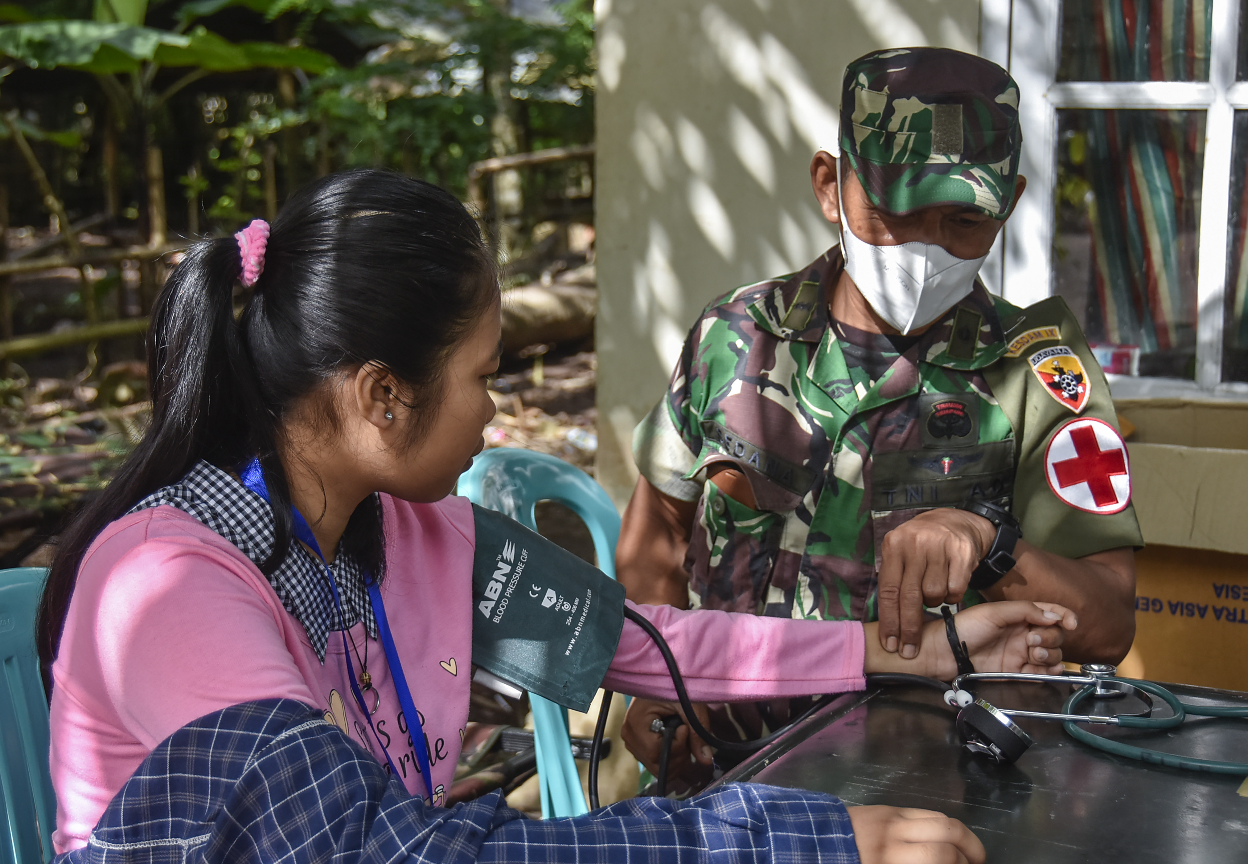 Seorang tenaga kesehatan TNI memeriksa tekanan darah seorang warga.