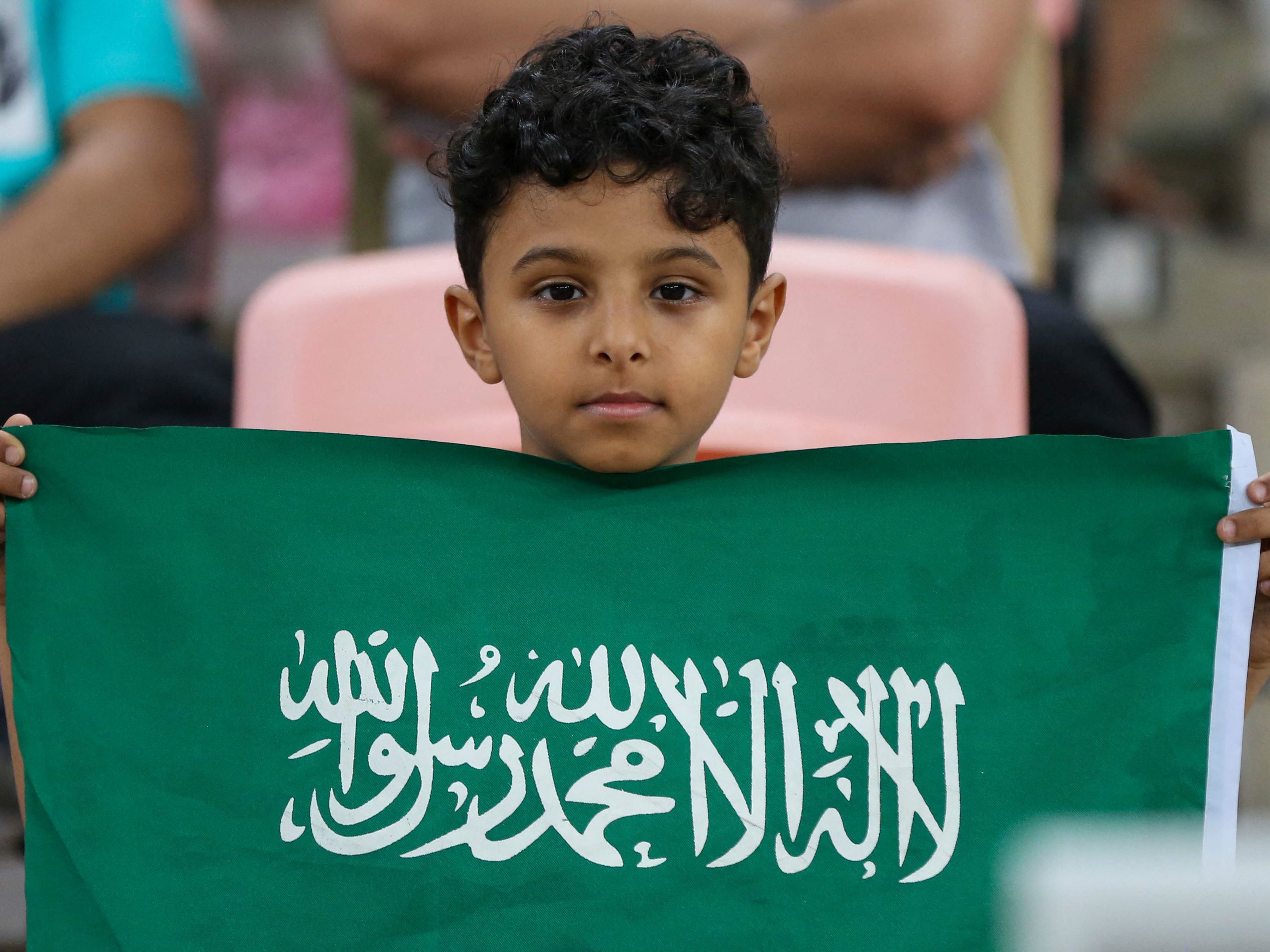 Seorang anak memegang bendera Arab Saudi.