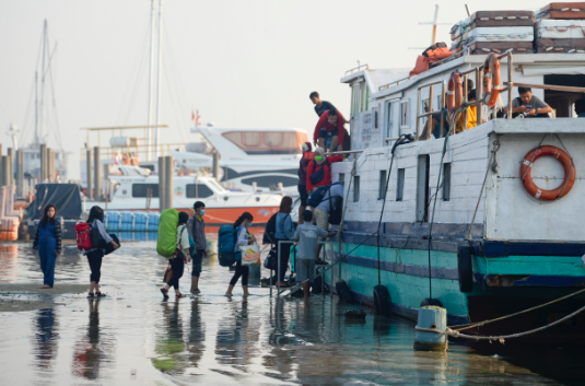 Calon penumpang antre untuk menaiki kapal motor saat terjadinya banjir rob di Pelabuhan Kali Adem, Muara Angke, Jakarta, Rabu (5/1/2022)