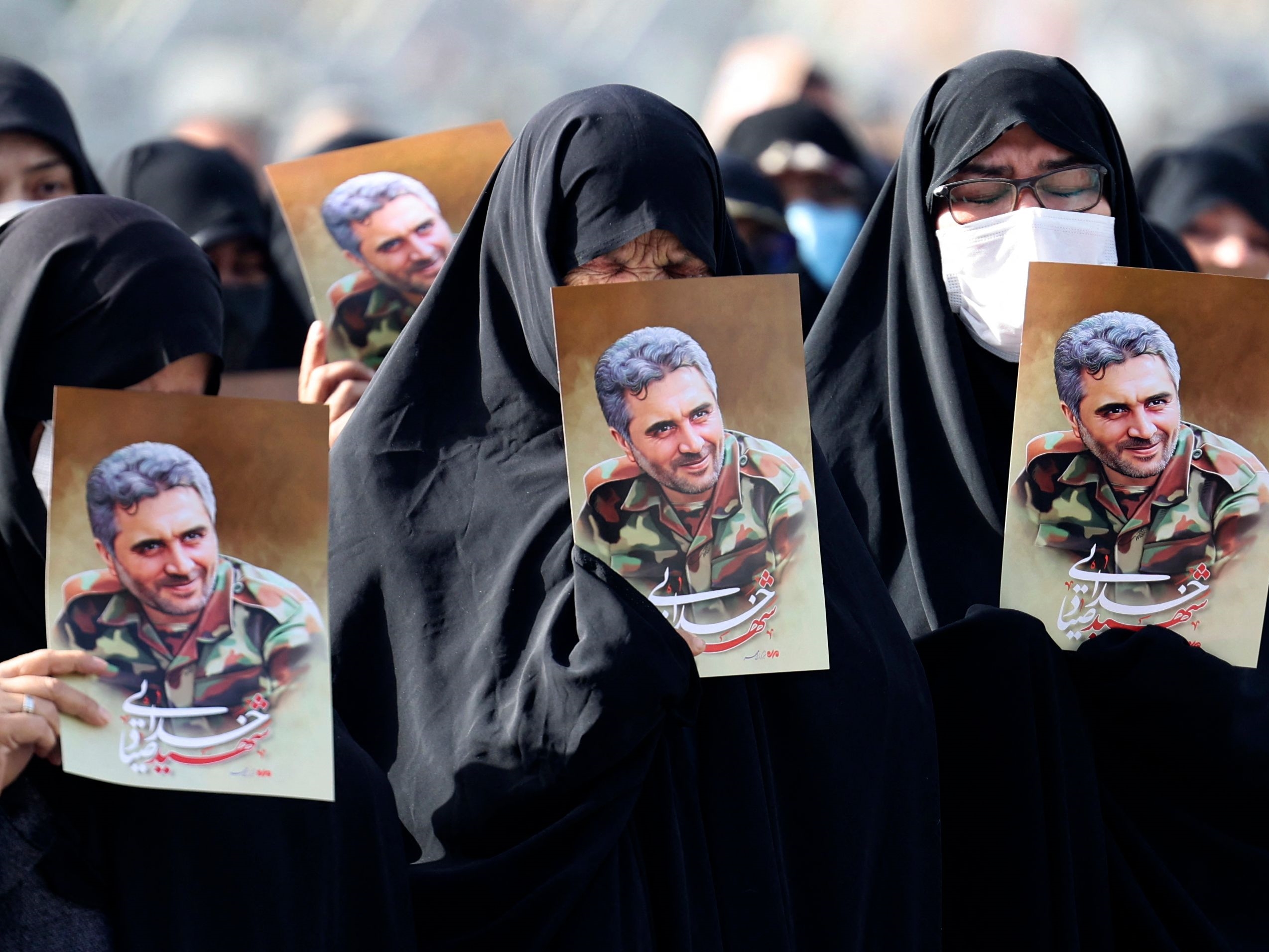 Wanita Iran mengangkat potret kolonel Pengawal Revolusi Sayyad Khodai selama prosesi pemakamannya di alun-alun Imam Hussein di Teheran.