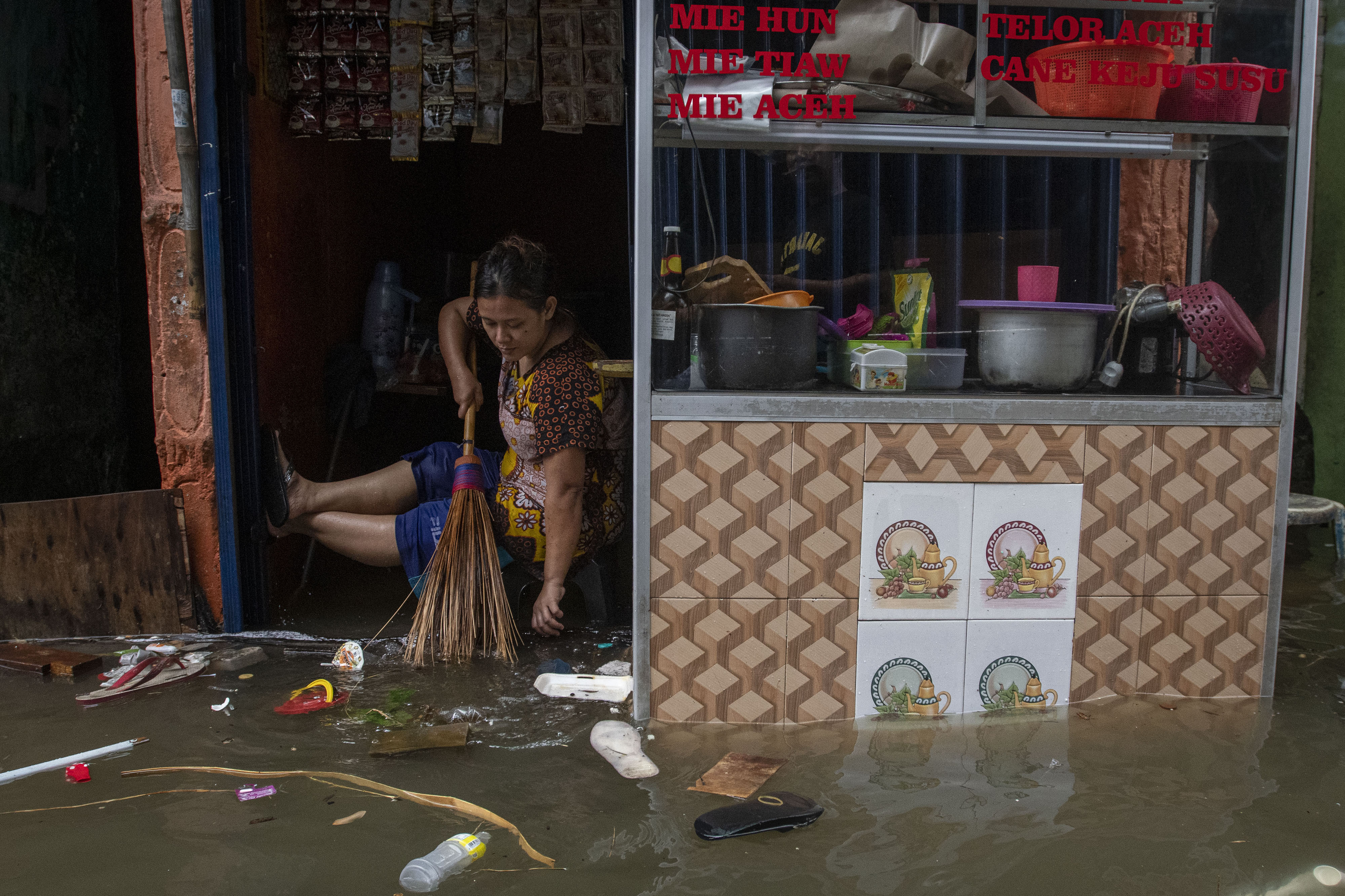 Warga membersihkan warungnya yang terendam rob atau banjir pasang air laut di Ancol, Pademangan, Jakarta, tahun lalu.