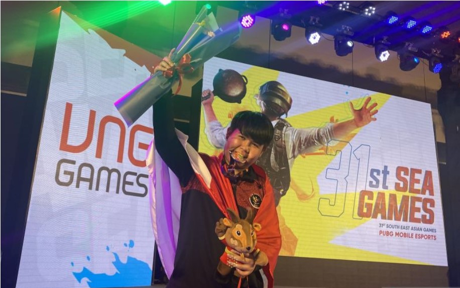 Atlet esport Alan Raynold Kumaseh menggigit medali perak SEA Games dari nomor PUBG Mobile, Selasa (17/5).