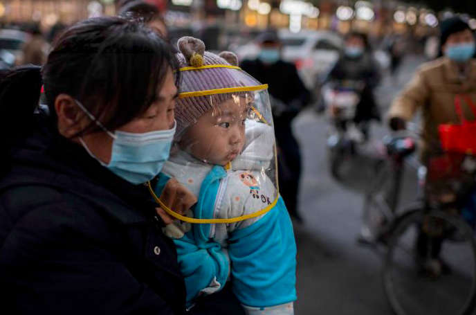 NICOLAS ASFOURI / AFP Seorang ibu menggendong bayinya di Wuhan, Tiongkok. 