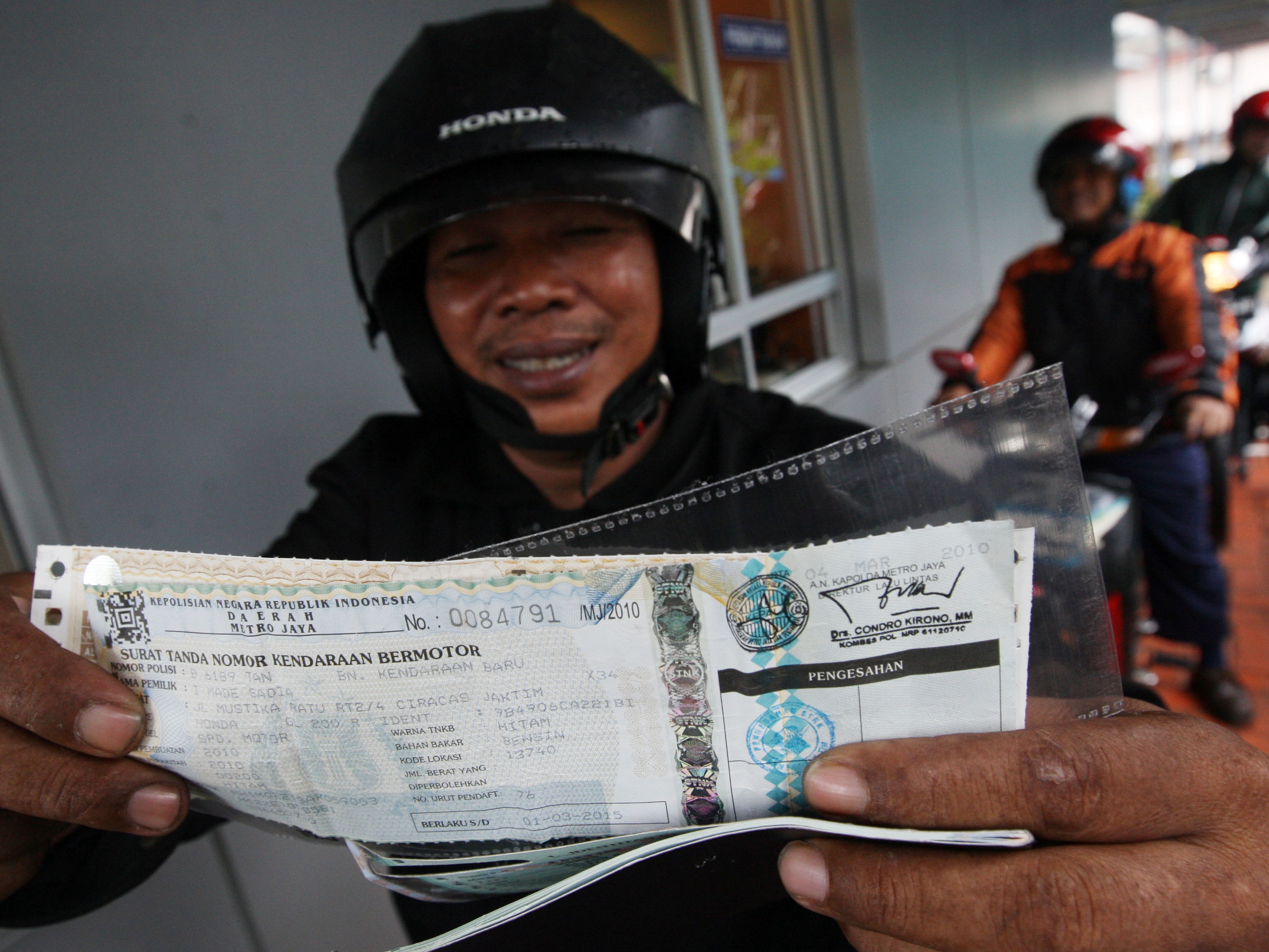 Pengendara sepeda motor menunjukkan STNK setelah melakukan pembayaran pajak kendaraan di loket layanan Samsat Drive Thru, Samsat Jakarta. 