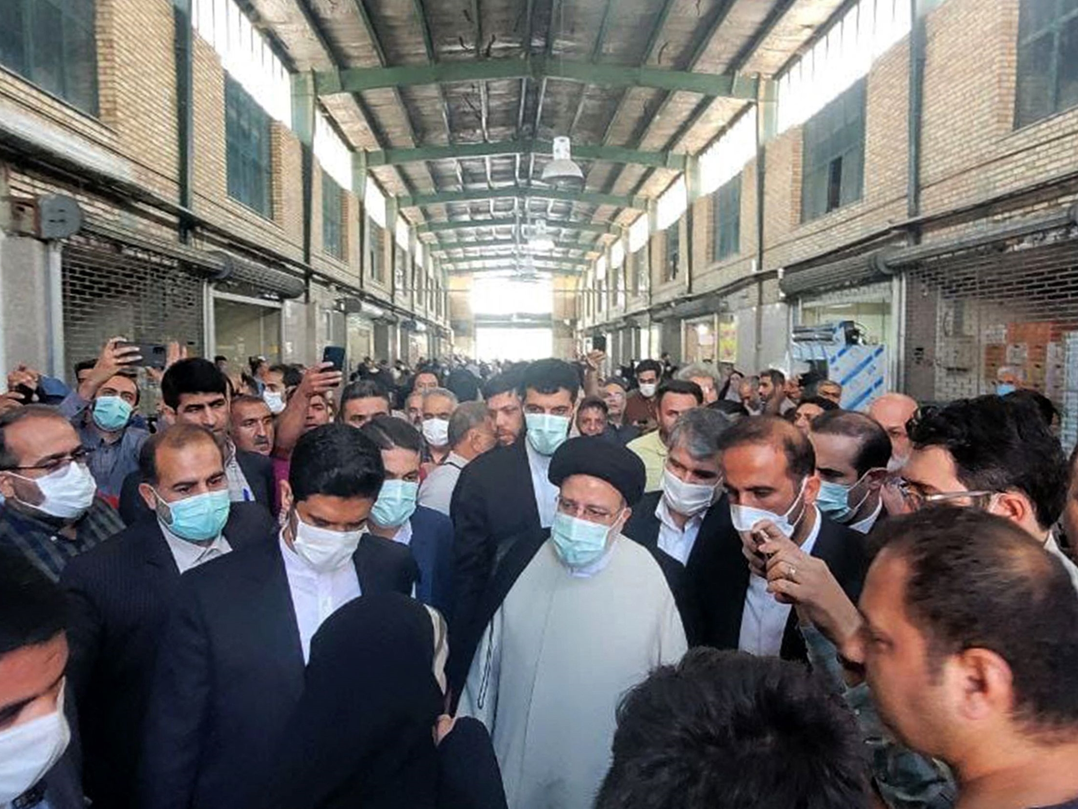 Presiden Iran Ebrahim Raisi (tengah) mengunjungi pasar di ibukota Teheran pada 13 Mei 2022 saat harga barang kebutuhan pokok melonjak.