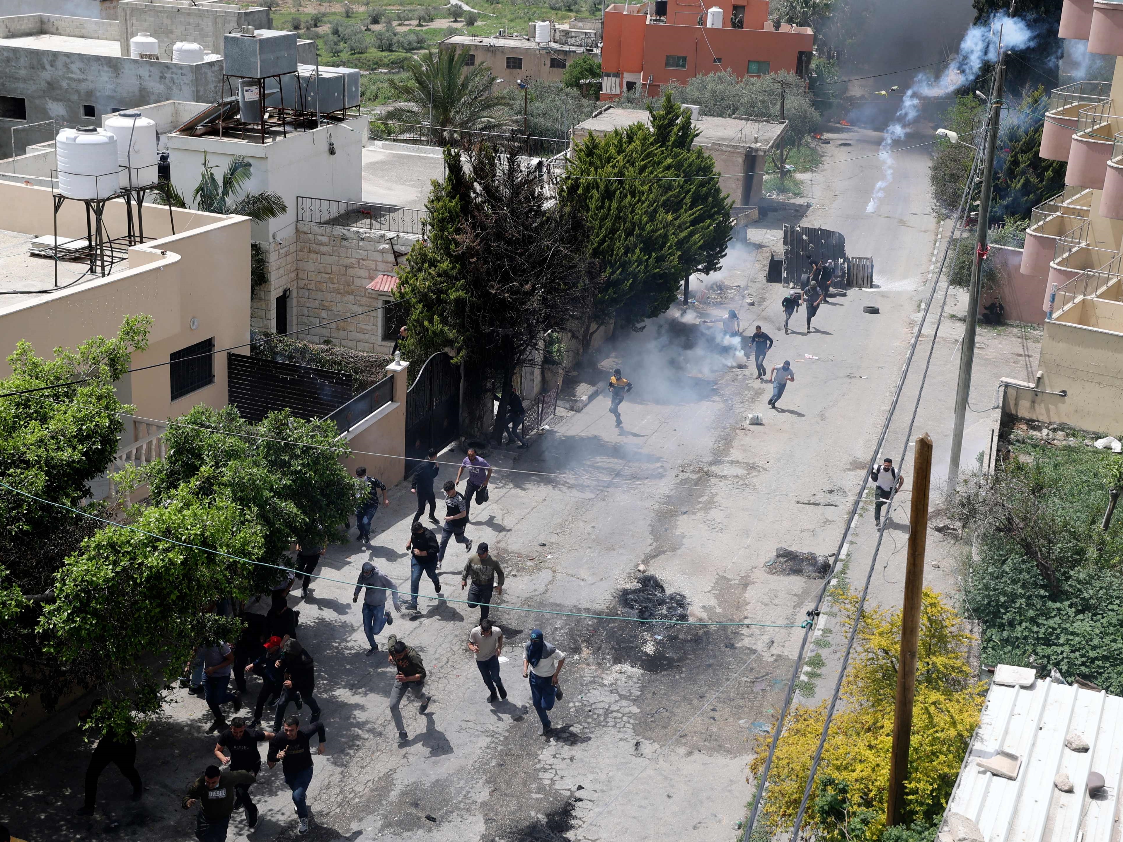 Para pengunjuk rasa Palestina berlari mencari perlindungan ketika pasukan Israel menembakkan gas air mata selama bentrokan.