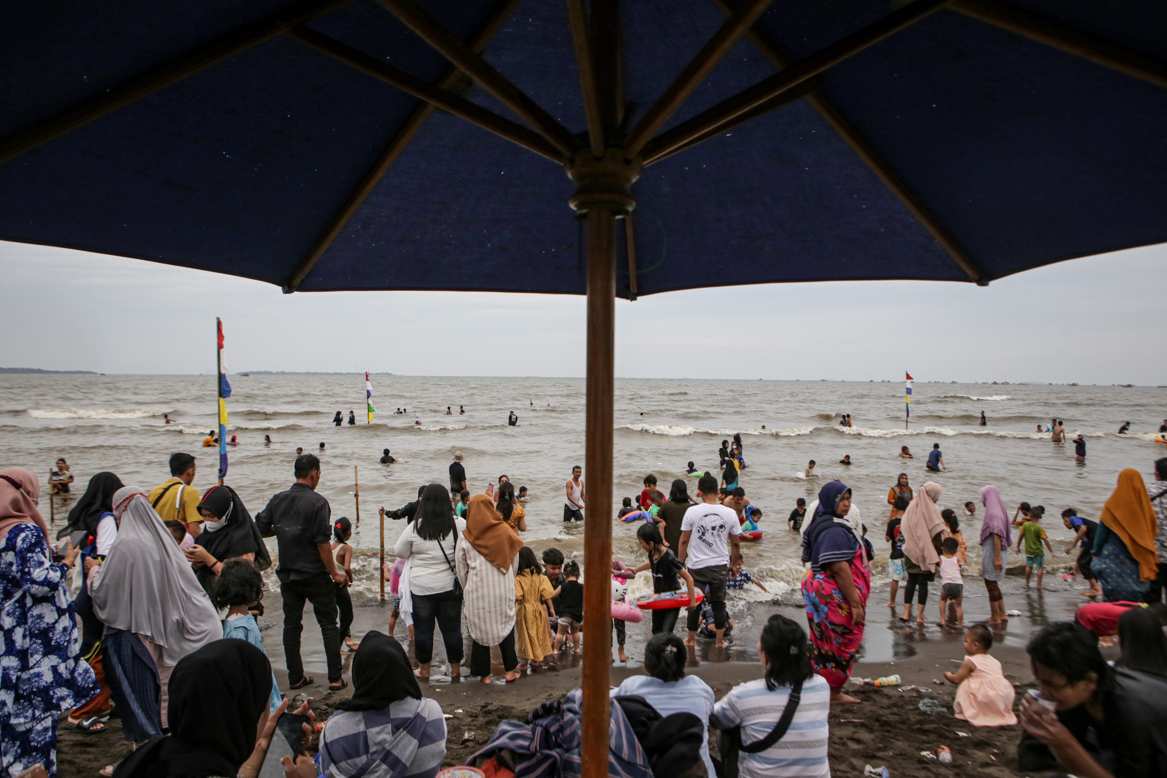 Ilustrasi pengunjung menikmati wisata pantai di masa libur Lebaran.