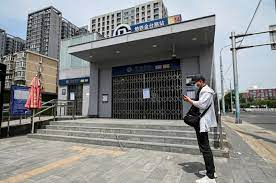 Warga berdiri di depan pintu masuk stasiun kereta bawah tanah yang ditutup di Beijing, Tiongkok. 