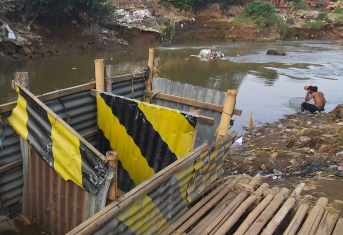 Seorang warga mandi di dekat bilik kakus atau jamban di kawasan Kampung Melayu, Jakarta.
