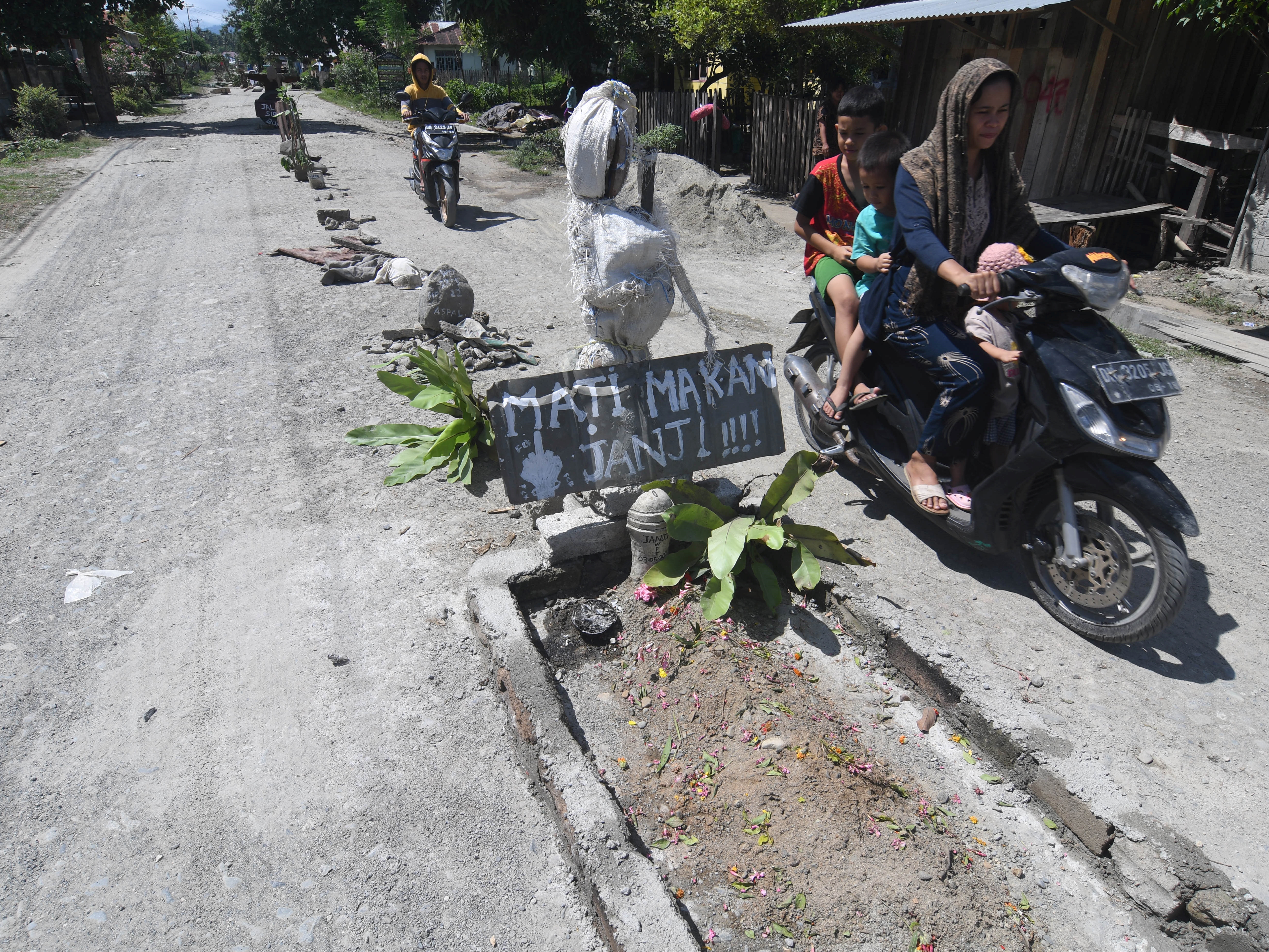 Pengendara sepeda motor melintas di dekat makam yang dibuat warga, di Labuan Panimba, Kabupaten Donggala, Sulawesi Tengah, Rabu (25/5/2022).