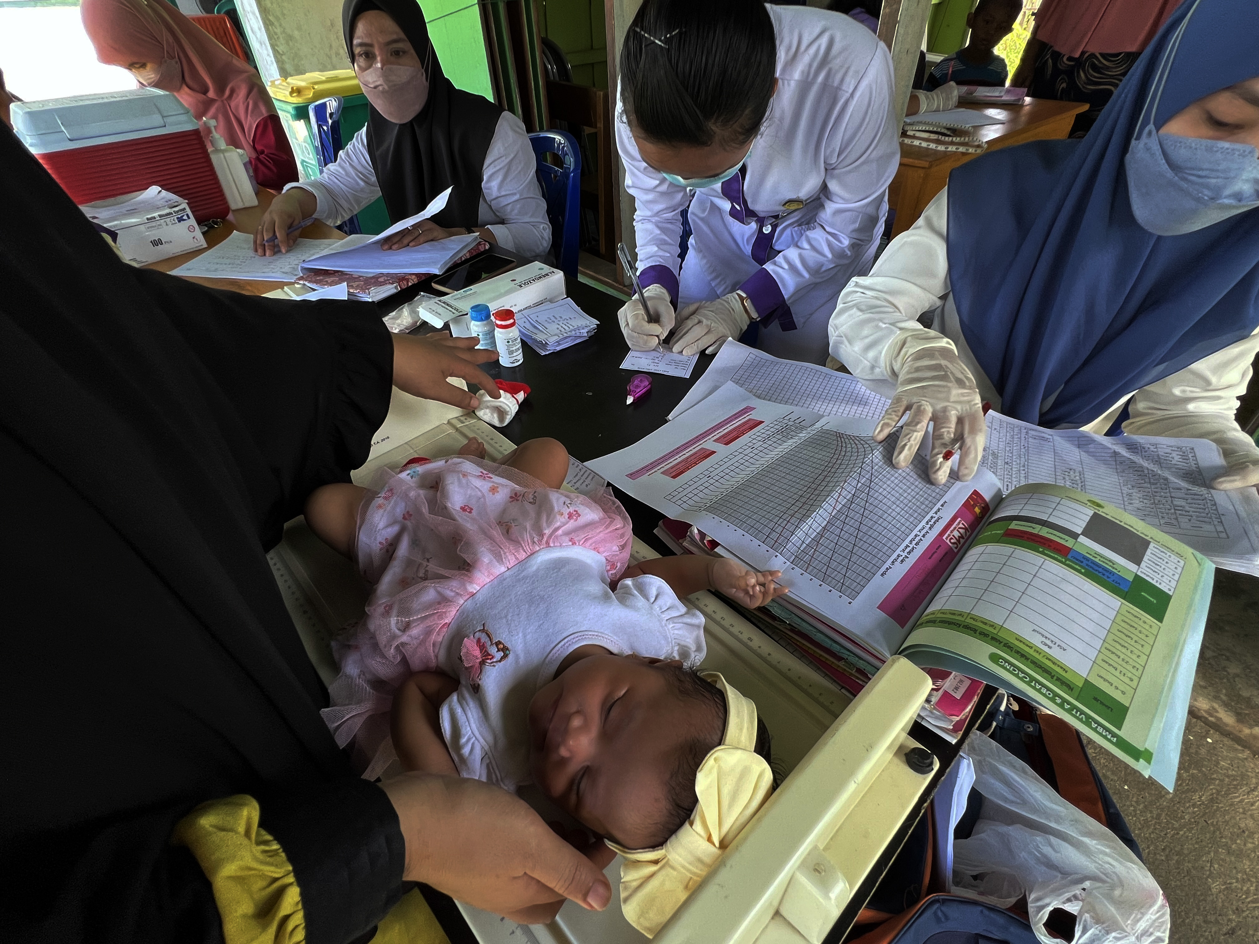 Petugas kesehatan memeriksa bayi saat imunisasi di posyandu.