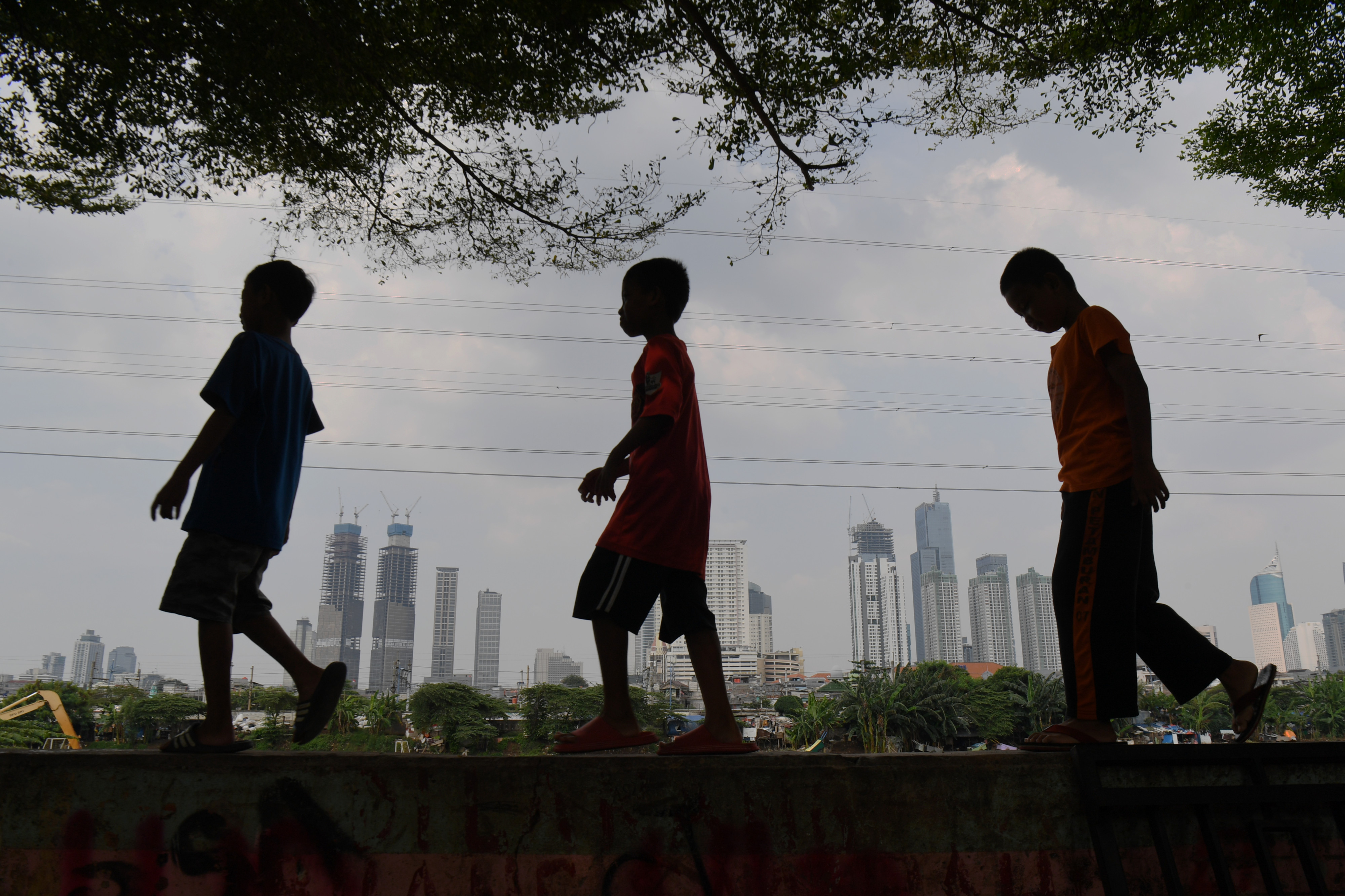 Ilustrasi anak-anak yang bermain dengan latar belakang gedung perkantoran.